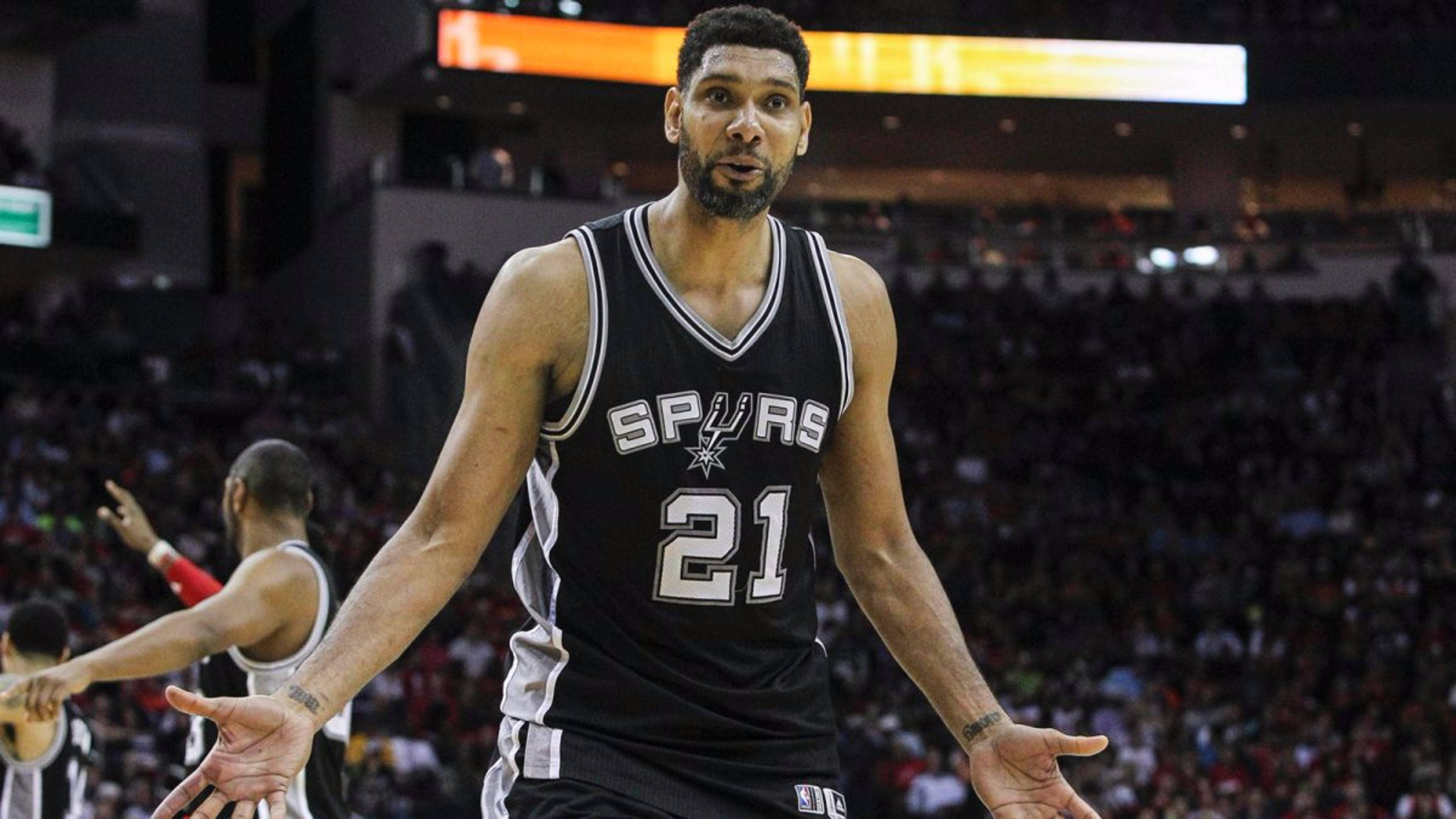Tim Duncan 桌布 壁紙 — 一名身穿馬刺球衣的籃球運動員在場館燈光下比賽時張開雙手做手勢。