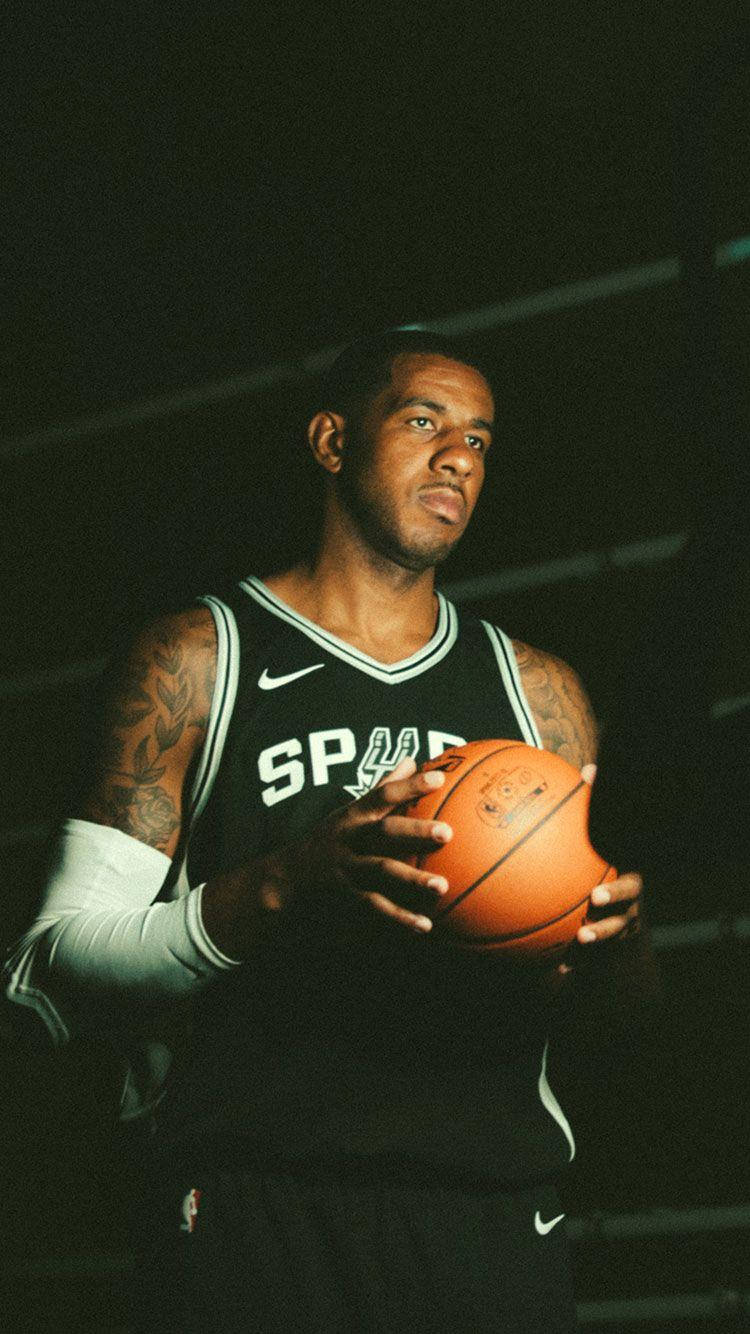 Lamarcus Aldridge 桌布 壁紙 — 一名身穿馬刺球衣的籃球運動員在戲劇性的工作室燈光下拿著球，手臂上的刺青清晰可見。