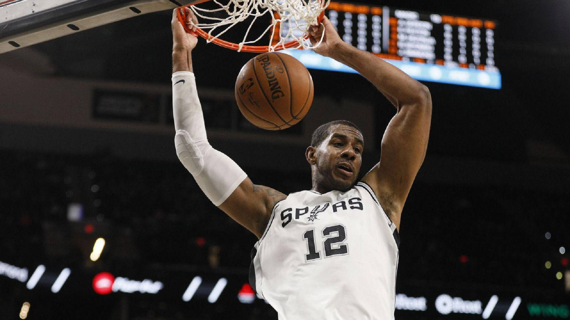 Lamarcus Aldridge 桌布 壁紙 — 一名身穿馬刺隊球衣的籃球運動員在明亮的場館燈光下，以高度專注力灌籃。
