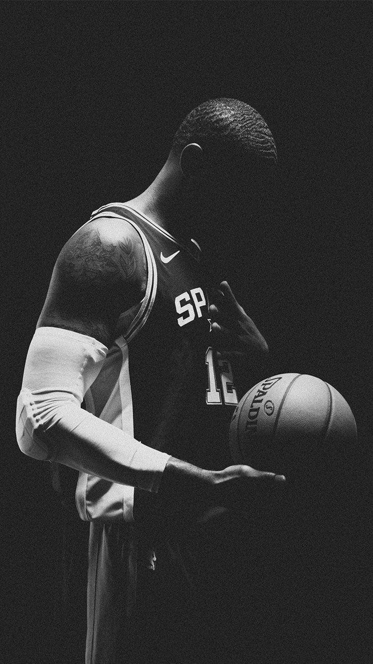 Lamarcus Aldridge 桌布 壁紙 — 一名身穿馬刺隊球衣的籃球運動員在戲劇性的黑白燈光下拿著球。