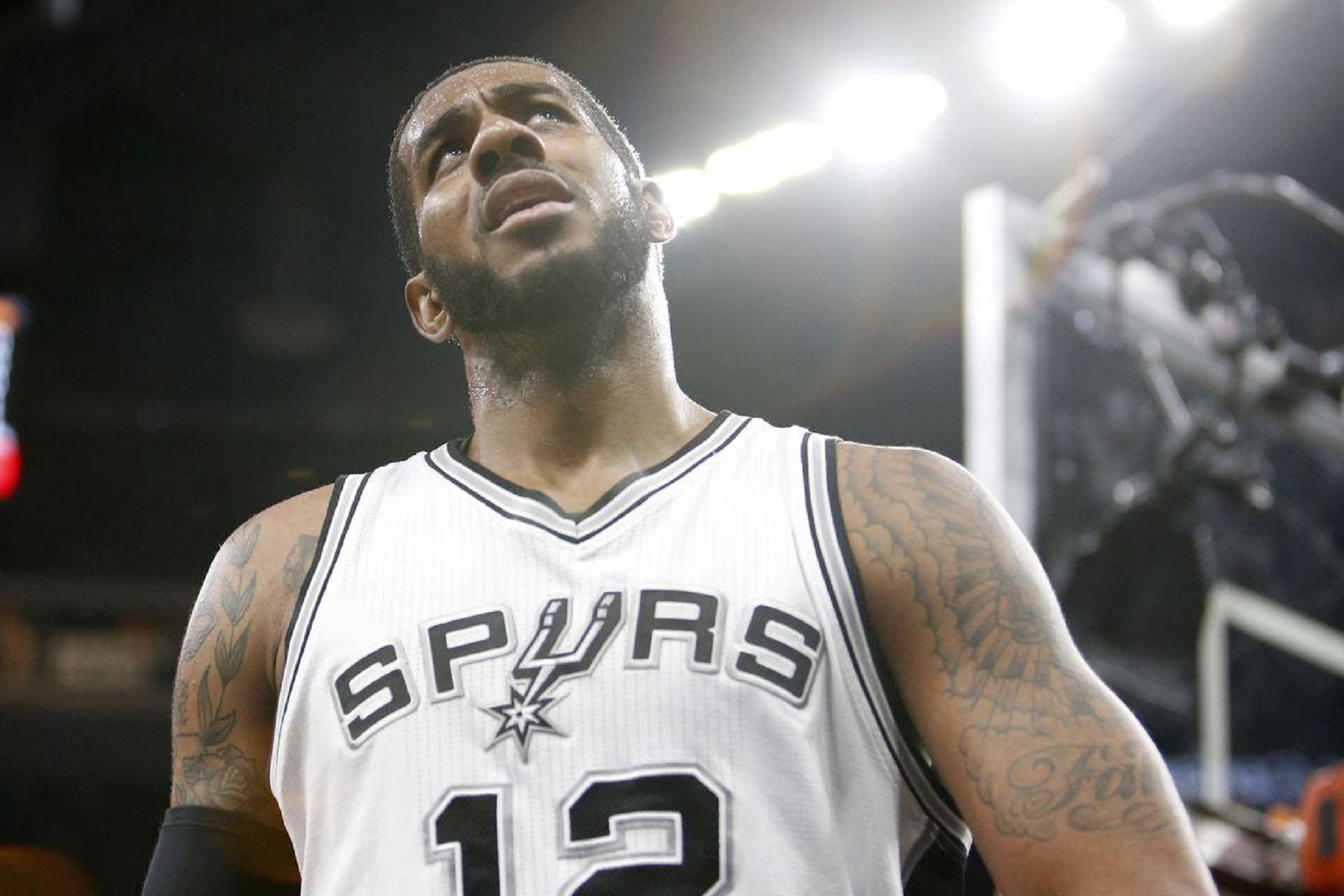 Lamarcus Aldridge 桌布 壁紙 — 一名身穿馬刺隊球衣的籃球運動員在明亮的場館燈光下，帶著強烈的專注力向上看。