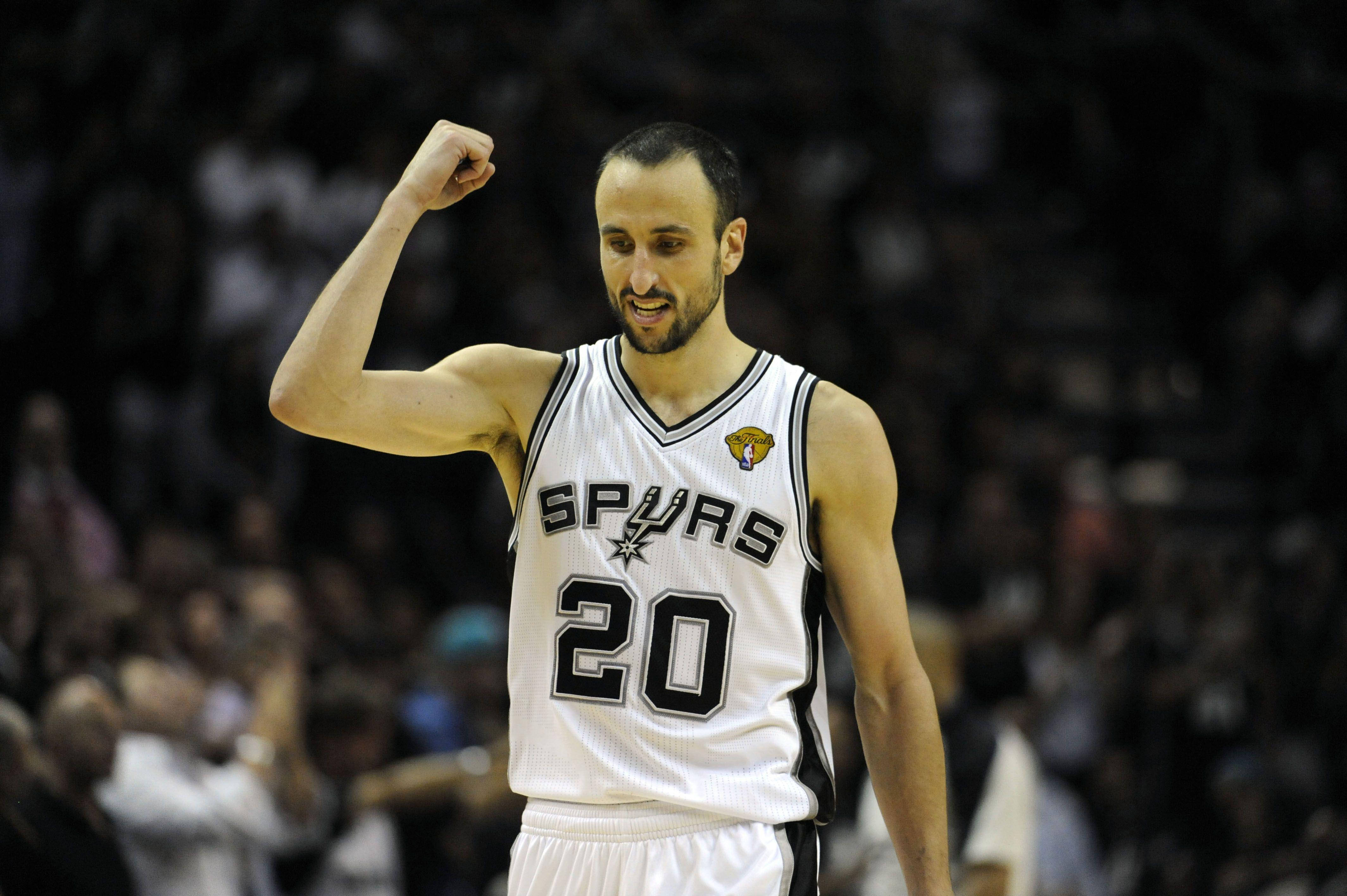 Manu 桌布 壁紙 — 一名身穿馬刺隊球衣的籃球運動員在場館燈光下，得意地笑著並彎曲手臂。