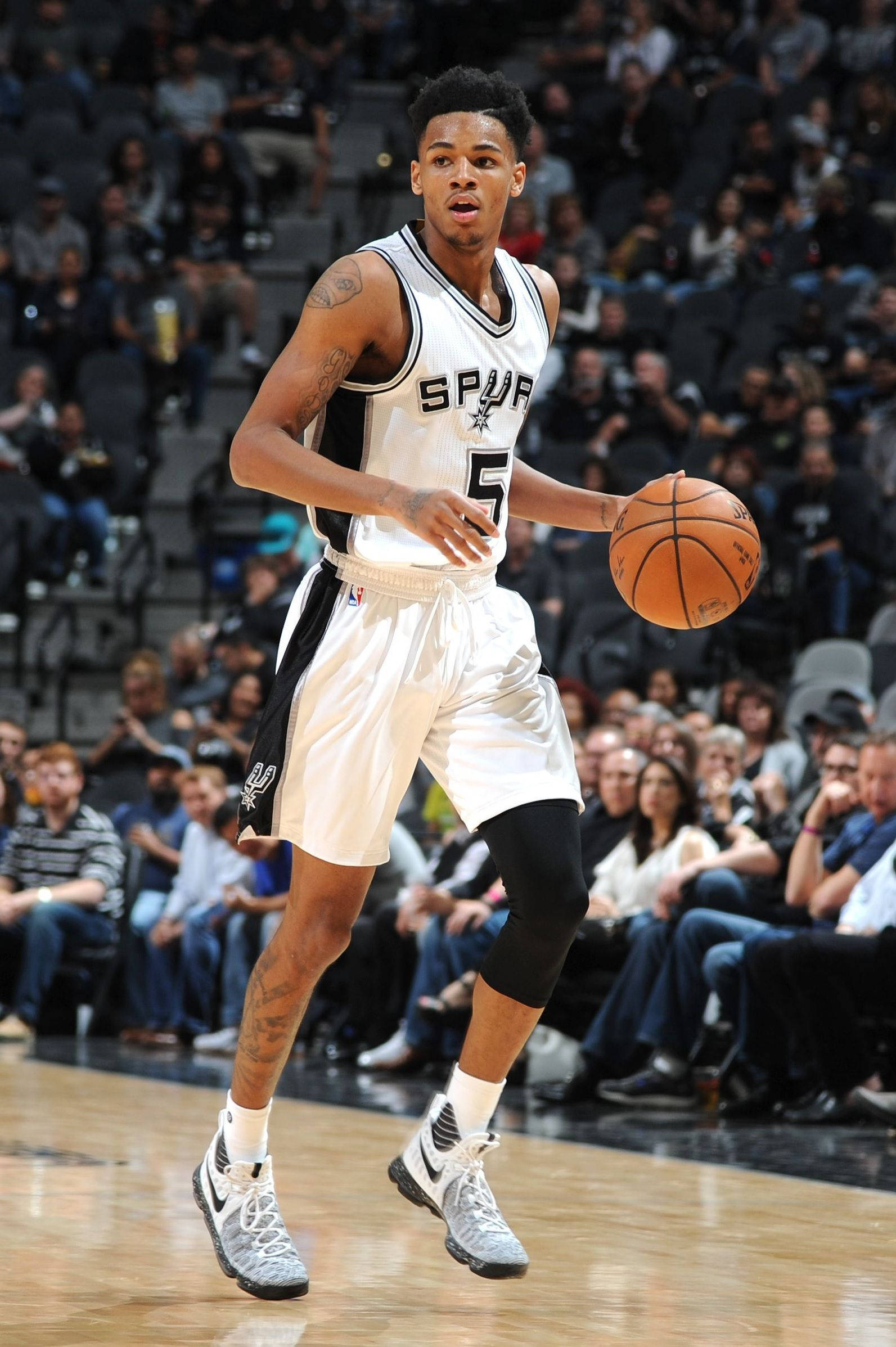 Dejounte Murray 桌布 壁紙 — 一名身穿馬刺隊球衣的籃球運動員在硬木球場上專注地運球，比賽中充滿強度。