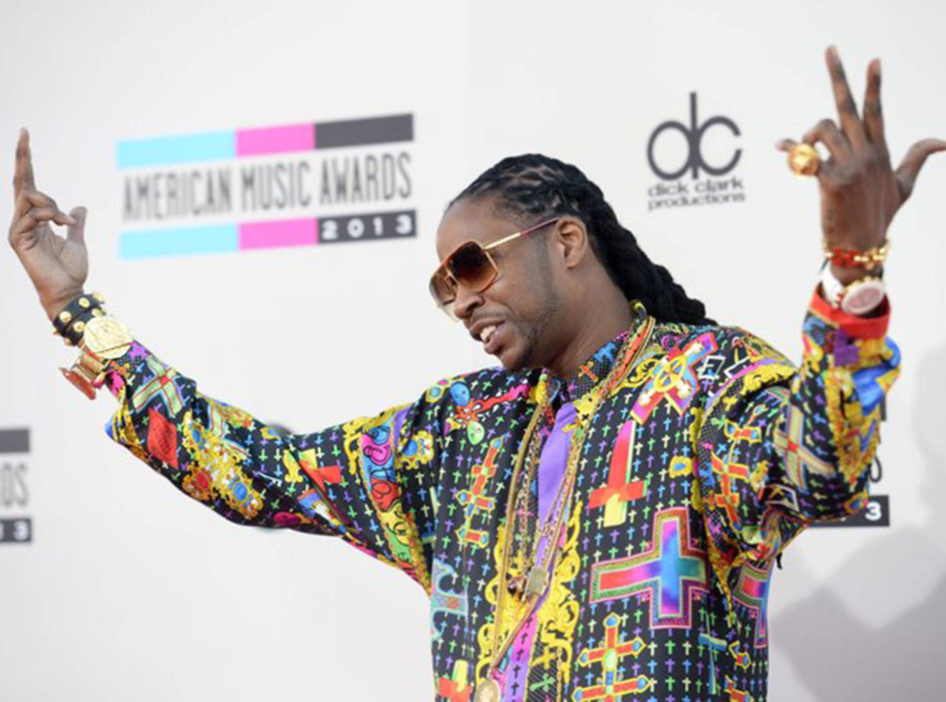 2 Chainz 桌布 壁紙 — 一名身穿鮮豔圖案外套和太陽眼鏡的男子在2013年美國音樂獎紅地毯上擺姿勢。