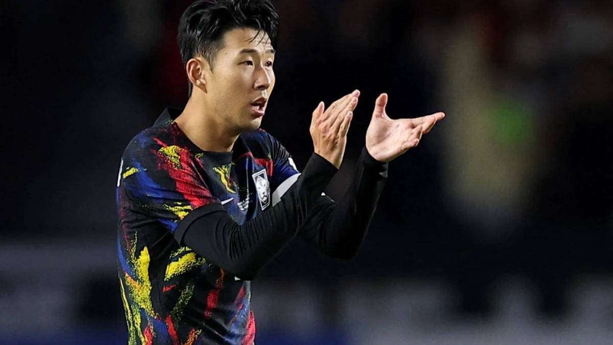Football Players 桌布 壁紙 — 一名身穿鮮豔多色球衣的足球員在球場燈光下的夜間比賽中熱情地做手勢。