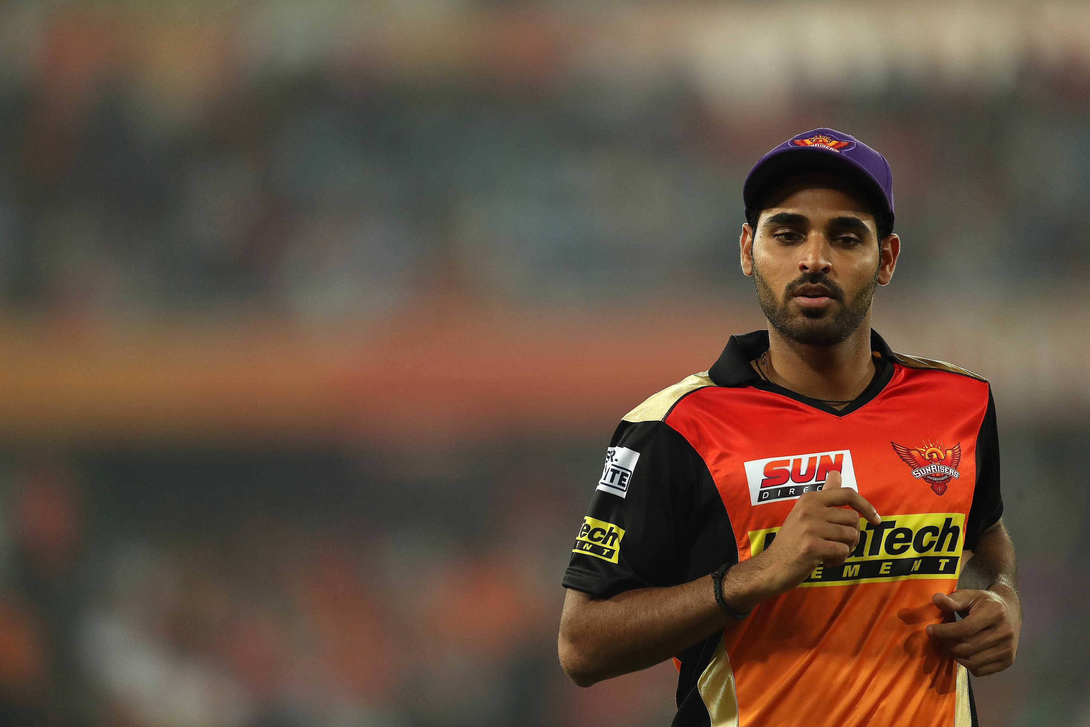 Sunrisers Hyderabad 桌布 壁紙 — 一名身穿鮮豔橙色和黑色球衣的板球運動員在體育場燈光下的體育場場地上奔跑。