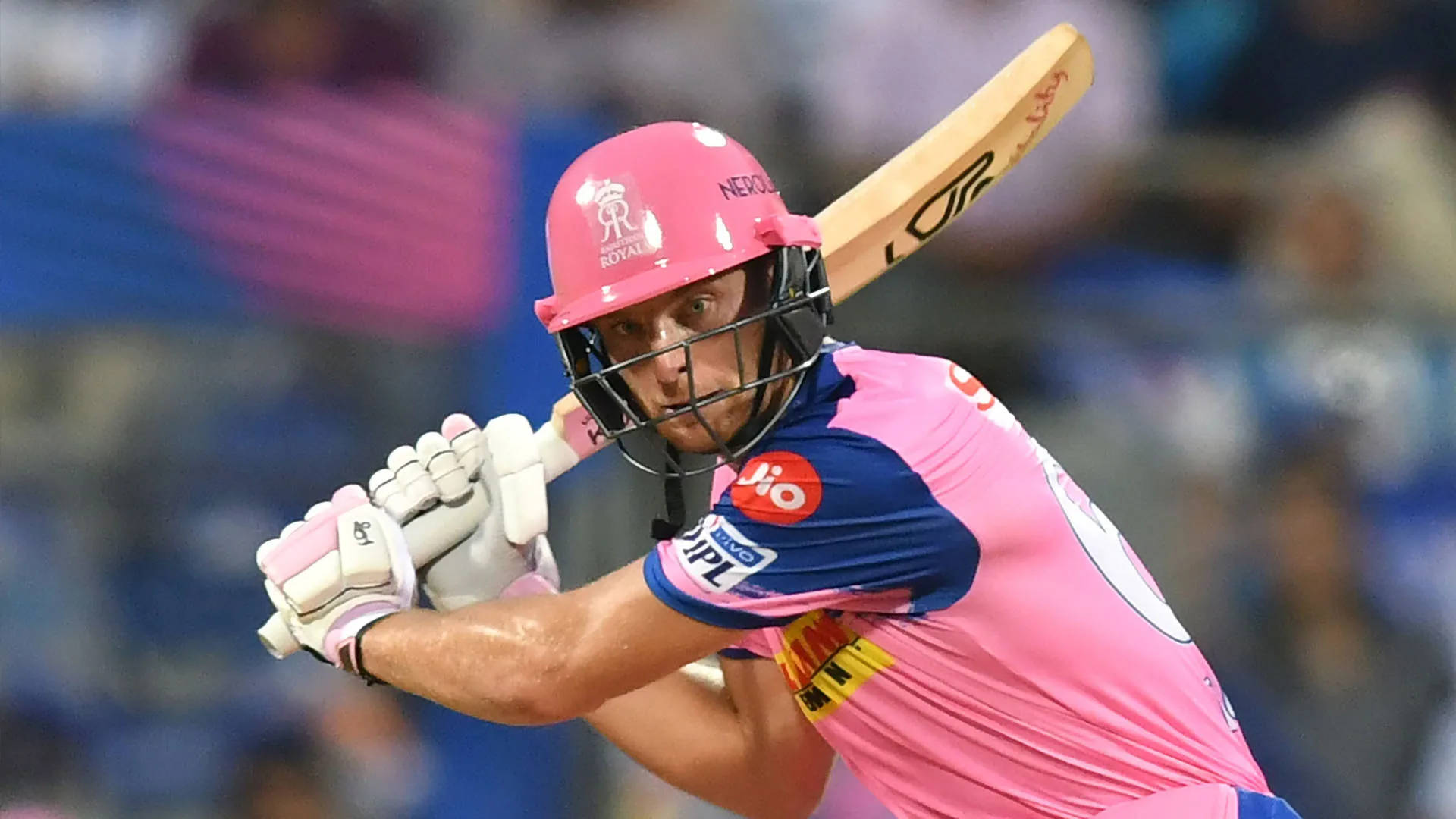 jos buttler 桌布 壁紙 — 一名身穿鮮豔粉紅色球衣的板球擊球手，在夜間比賽的球場燈光下，全神貫注地揮動球棒。
