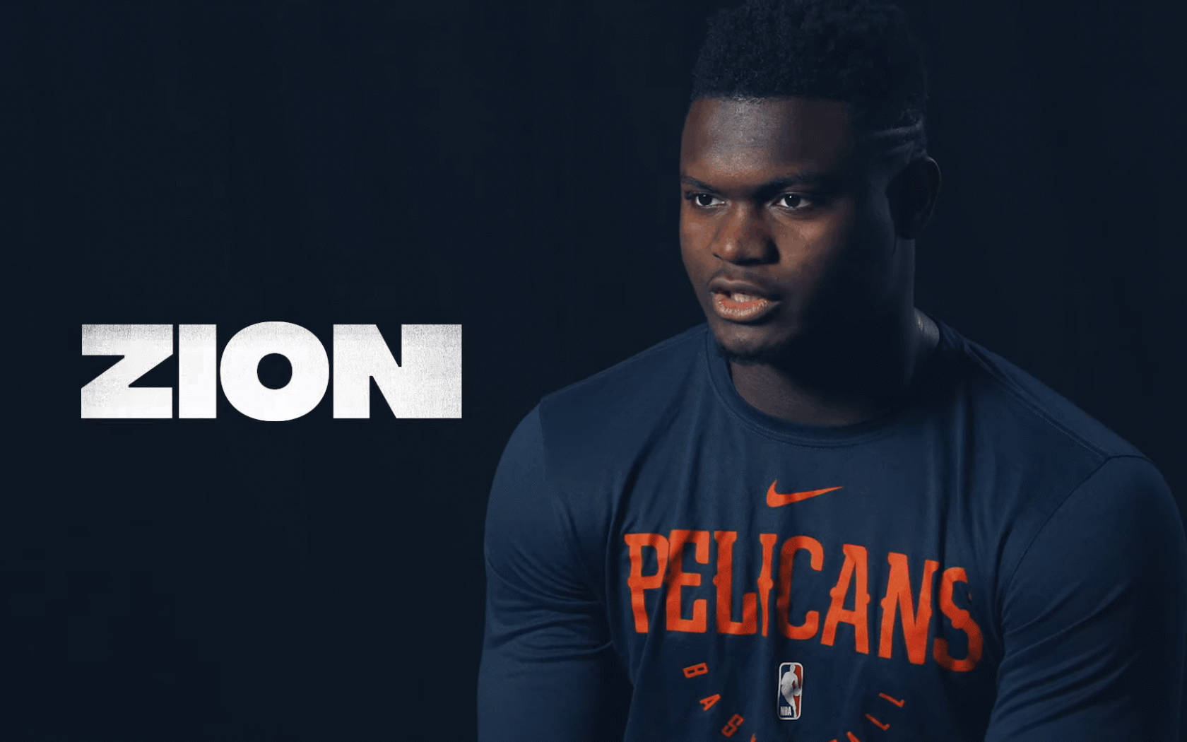 Zion 桌布 壁紙 — 一名身穿鵜鶘隊球衣的籃球運動員在深色背景下，以粗體白色文字顯示名字「ZION」，凝視著前方。