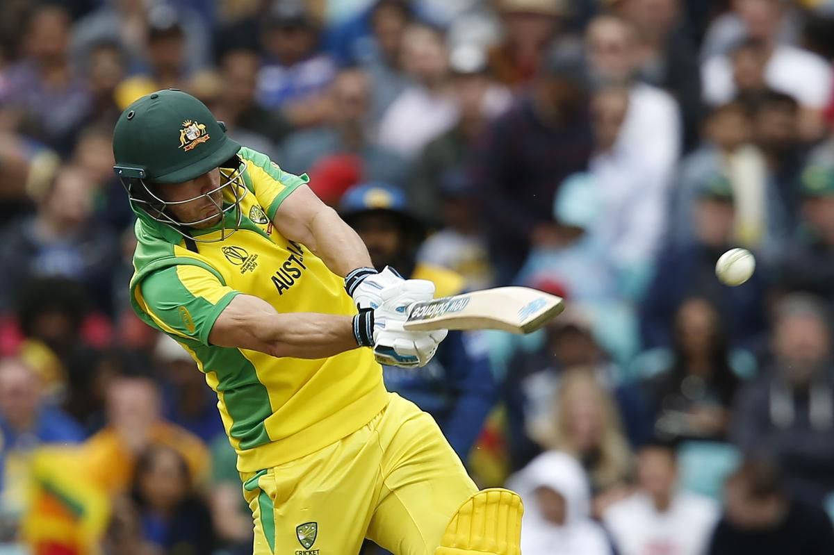 Aaron Finch 桌布 壁紙 — 一名身穿黃綠色球衣的澳洲板球運動員在日間比賽中揮動球棒擊球，背景有模糊的觀眾。