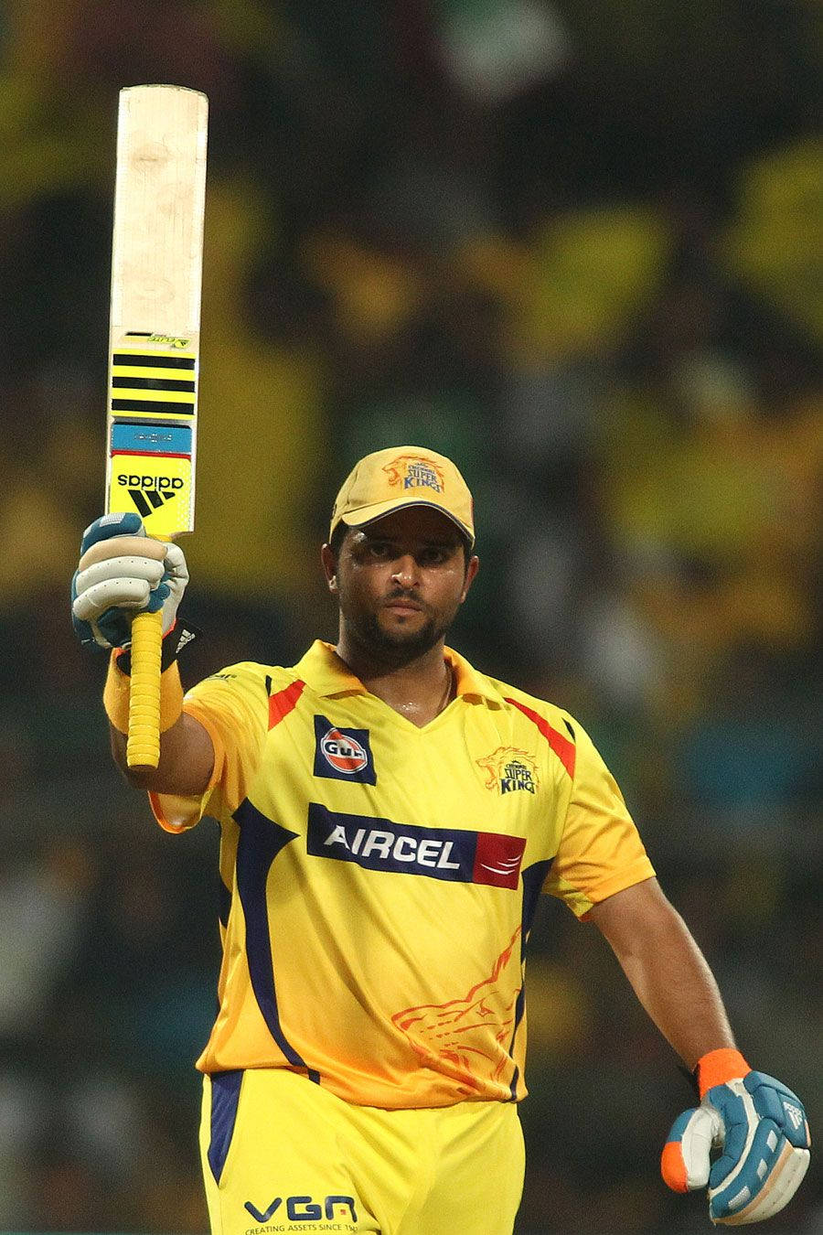 運動 桌布 壁紙 — 一名身穿黃色 Chennai Super Kings 球衣的板球運動員在球場燈光下高舉球棒，神情專注。