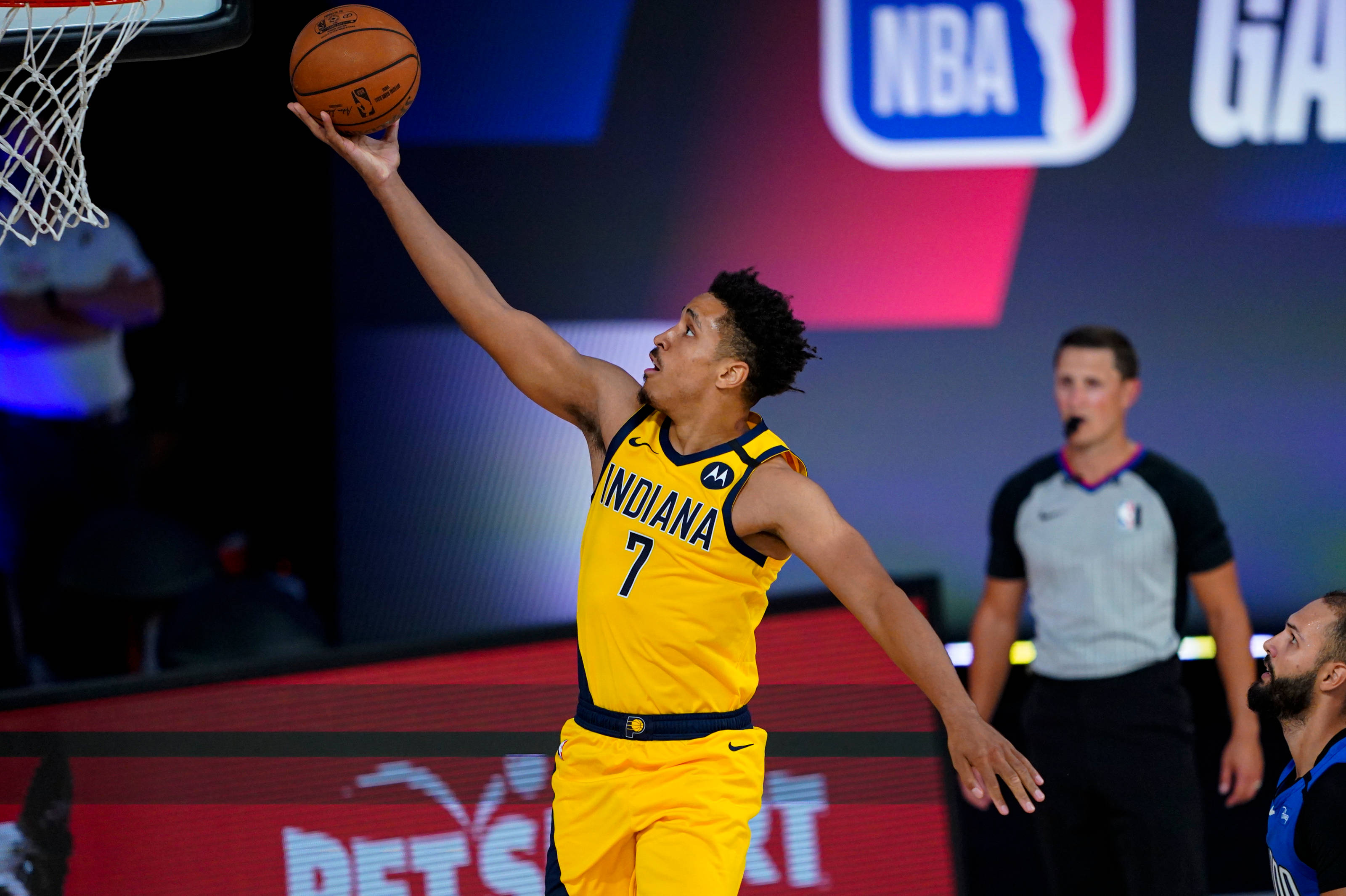 malcolm brogdon 桌布 壁紙 — 一名身穿黃色印第安納球衣的籃球運動員在明亮的場館燈光下於NBA比賽中灌籃。