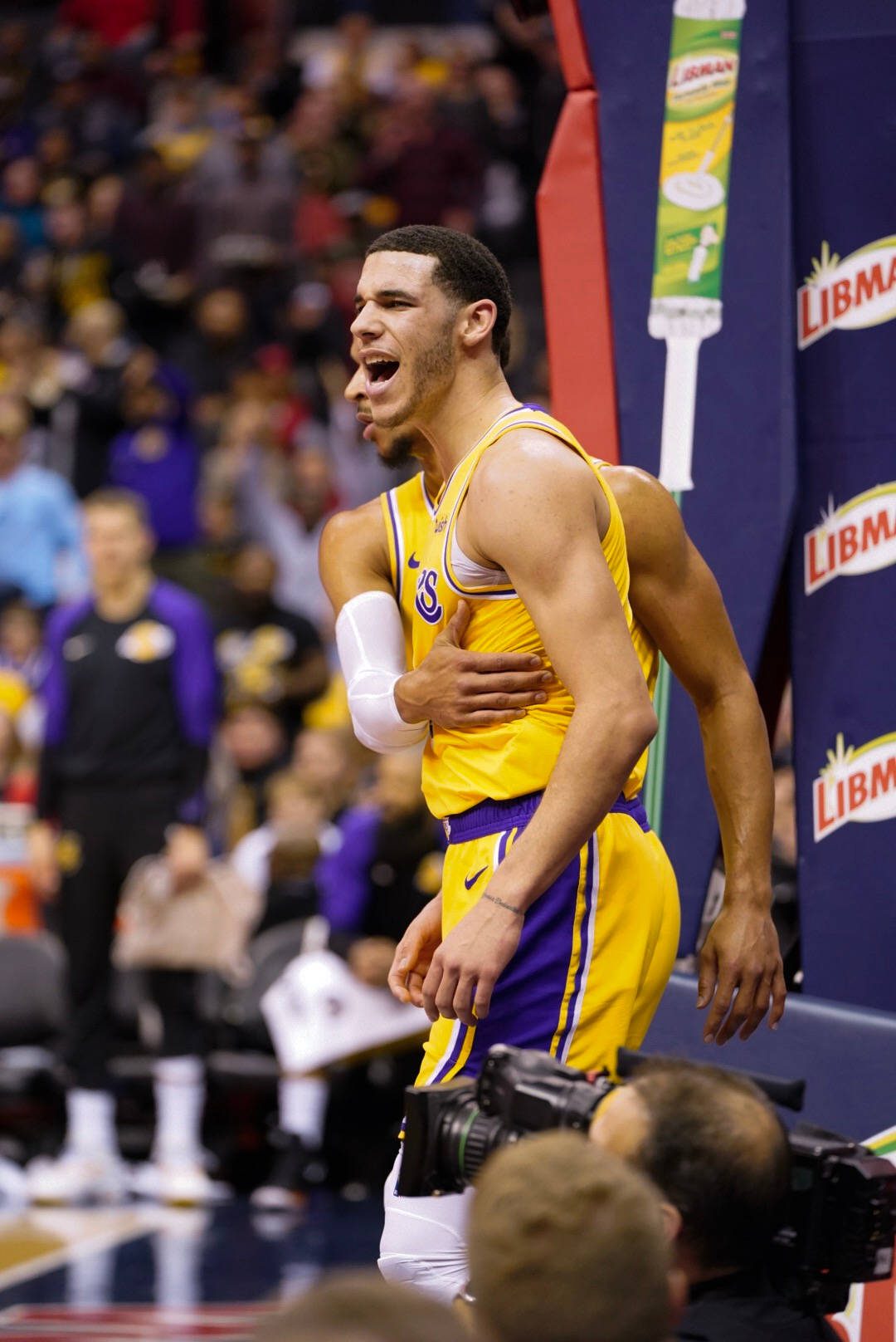 NBA 桌布 壁紙 — 一名身穿黃色和紫色球衣的籃球運動員在明亮的場館燈光下比賽期間張開雙臂慶祝。