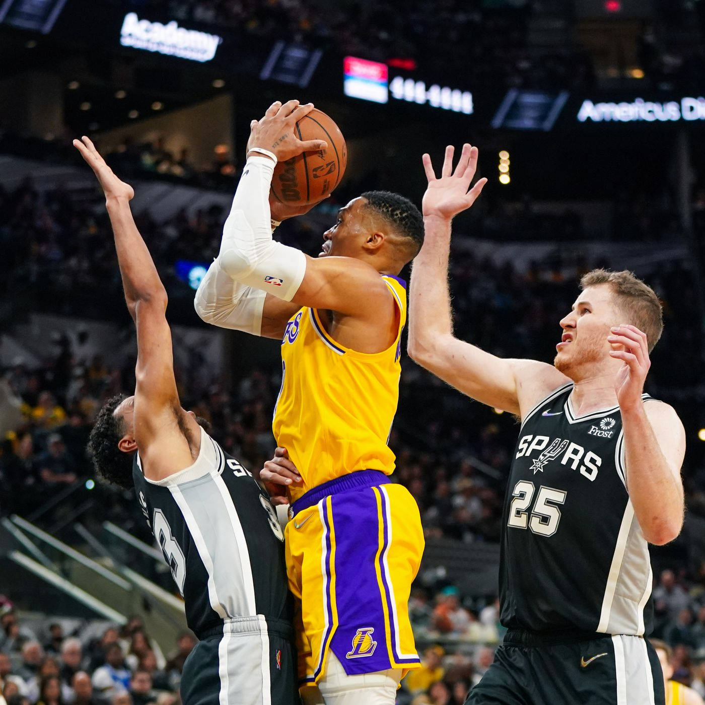 NBA 桌布 壁紙 — 一名身穿黃色和紫色球衣的籃球運動員跳起投籃，兩名身穿黑色球衣的防守球員舉起手臂阻擋。