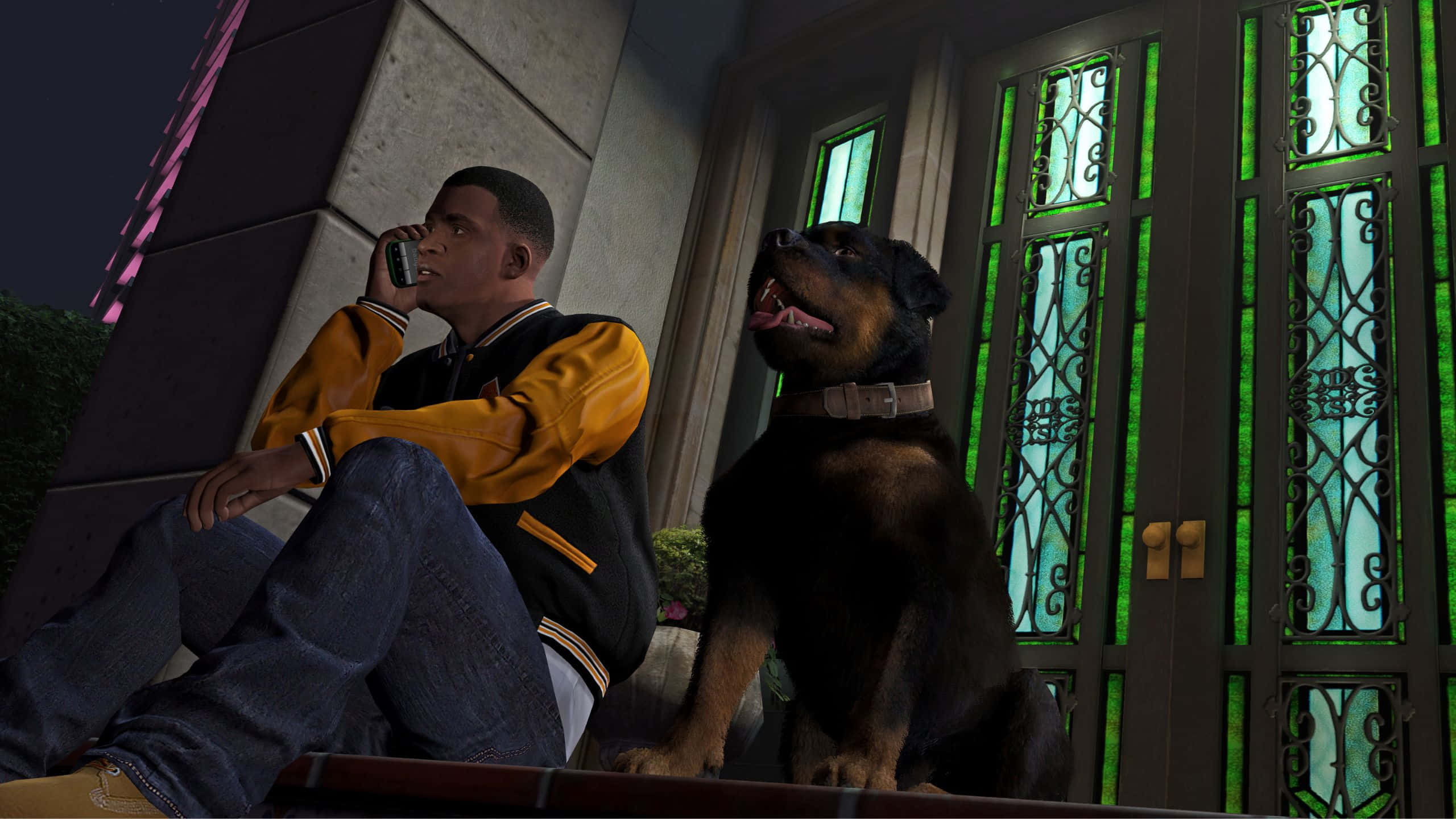 Grand Theft Auto V 桌布 壁紙 — 一名身穿黃色夾克的年輕男子在夜間於裝飾華麗的綠色燈光門旁與一隻羅威納犬一起講電話。