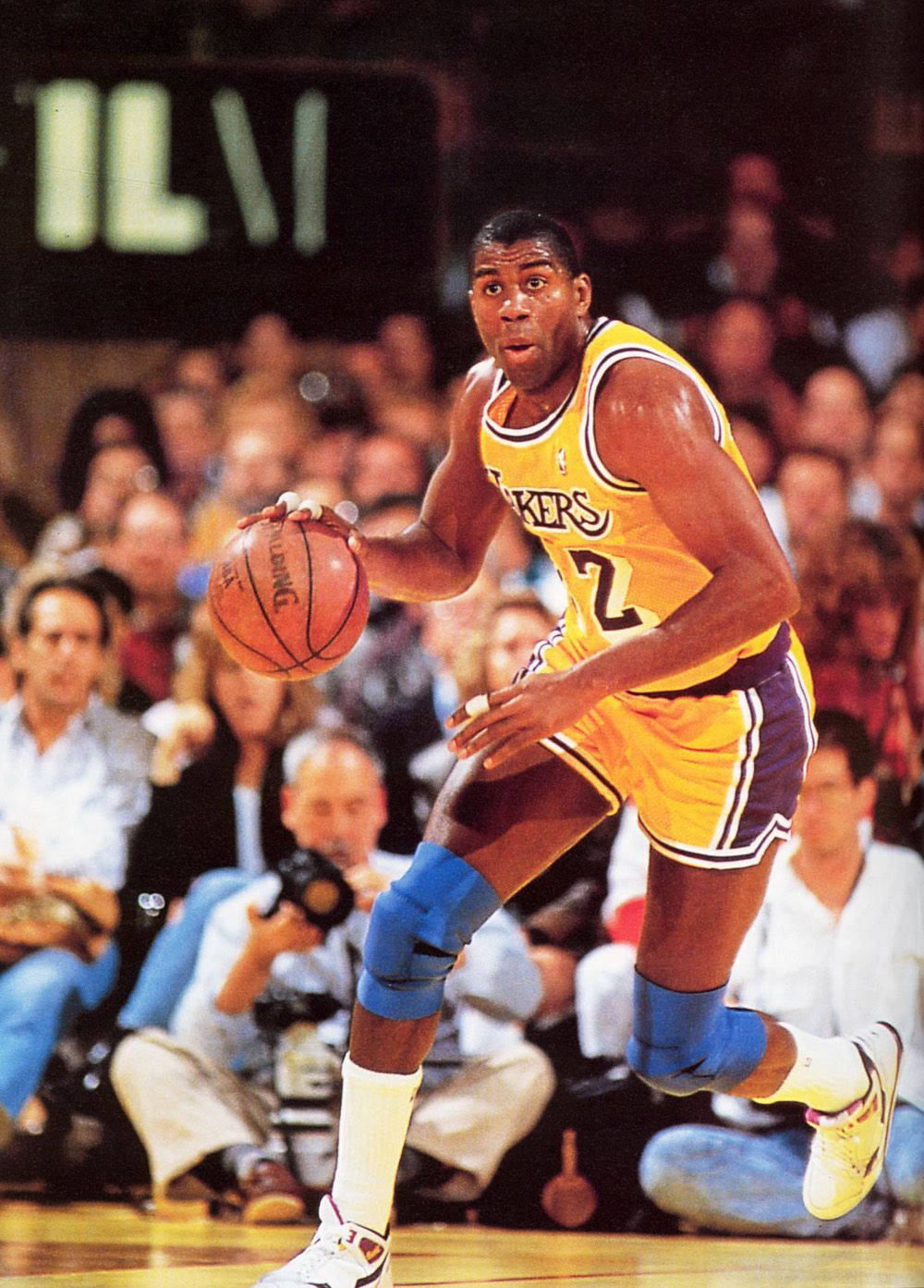 Magic Johnson 桌布 壁紙 — 一名身穿黃色湖人球衣的籃球運動員在比賽中激烈運球，背景是擠滿的人群。