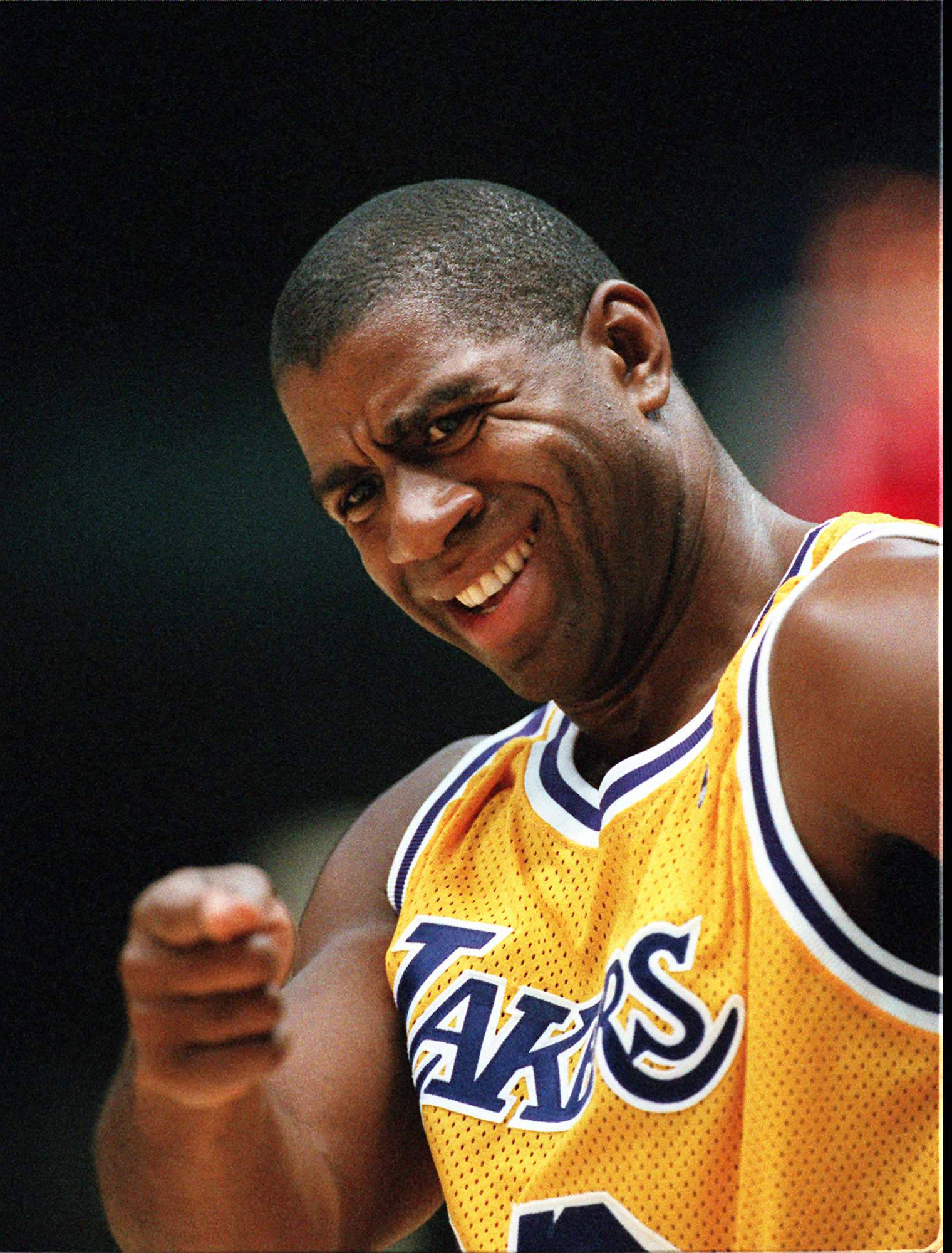 Magic Johnson 桌布 壁紙 — 一名身穿黃色湖人隊球衣的籃球運動員在比賽中微笑著向前指。