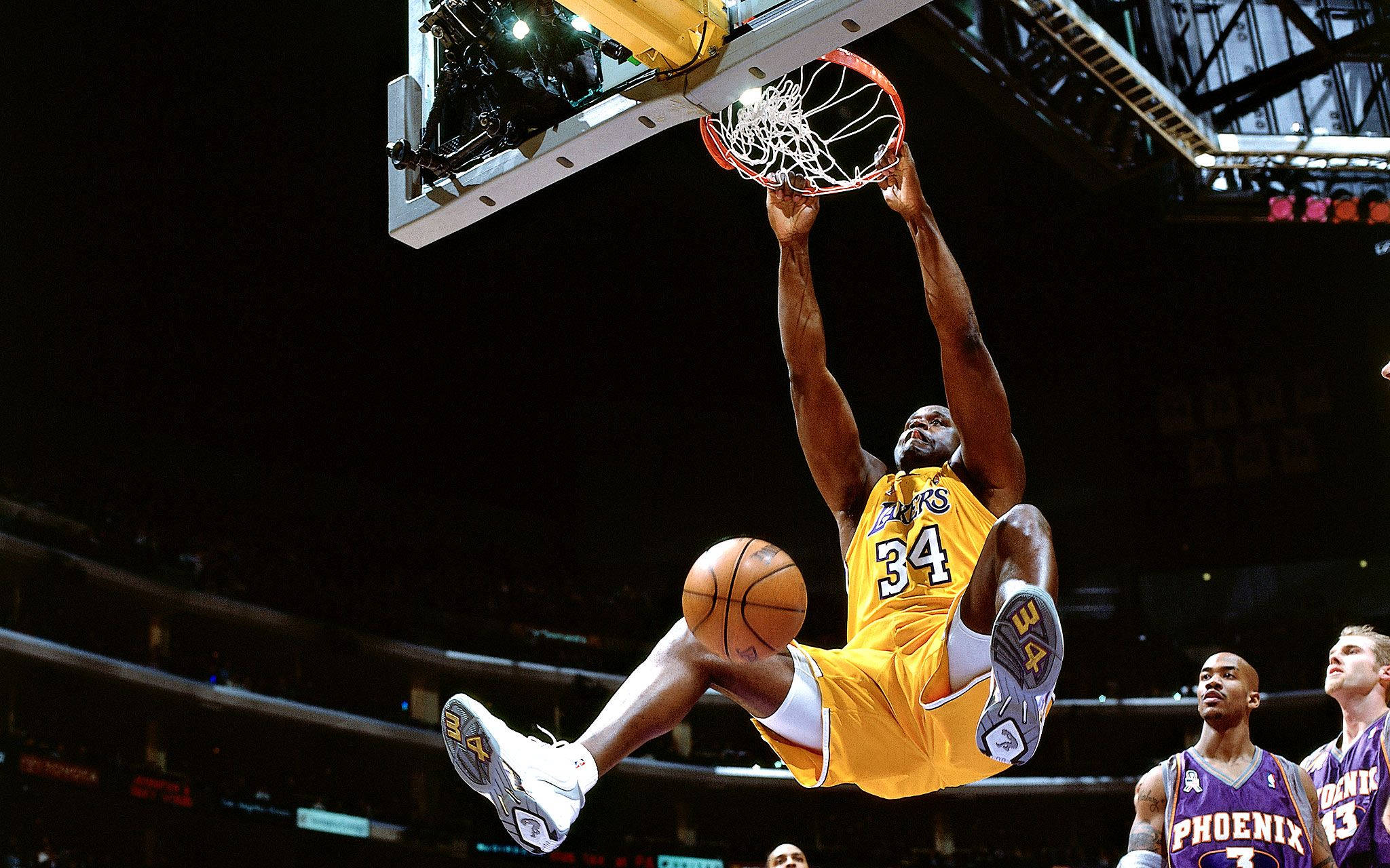 Shaquille O'neal 桌布 壁紙 — 一名身穿黃色湖人隊球衣的籃球運動員，在明亮的場館燈光下專注地灌籃。