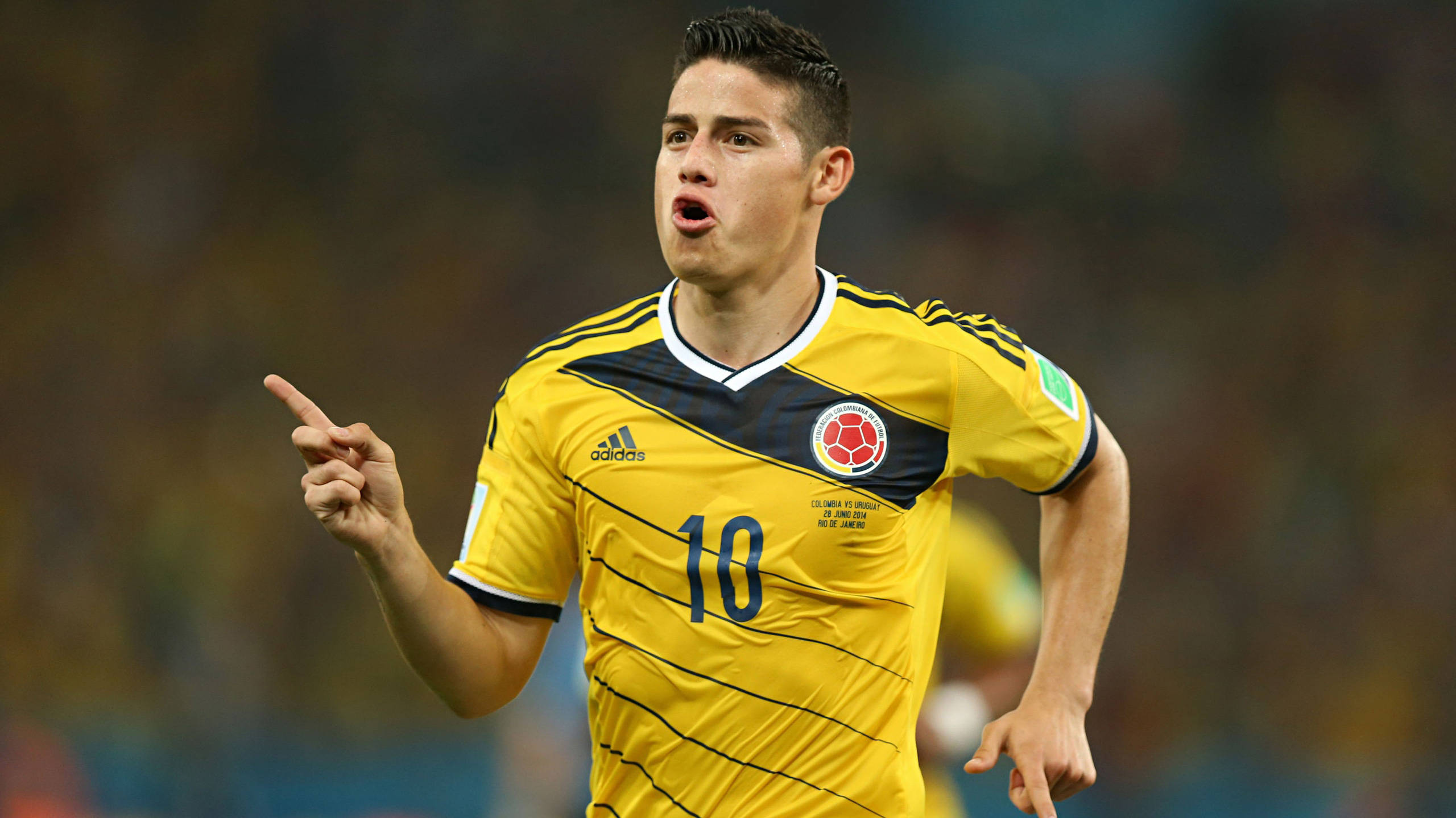 James Rodriguez 桌布 壁紙 — 一名身穿黃色球衣、背號10的哥倫比亞足球員在比賽中專注地向上指。