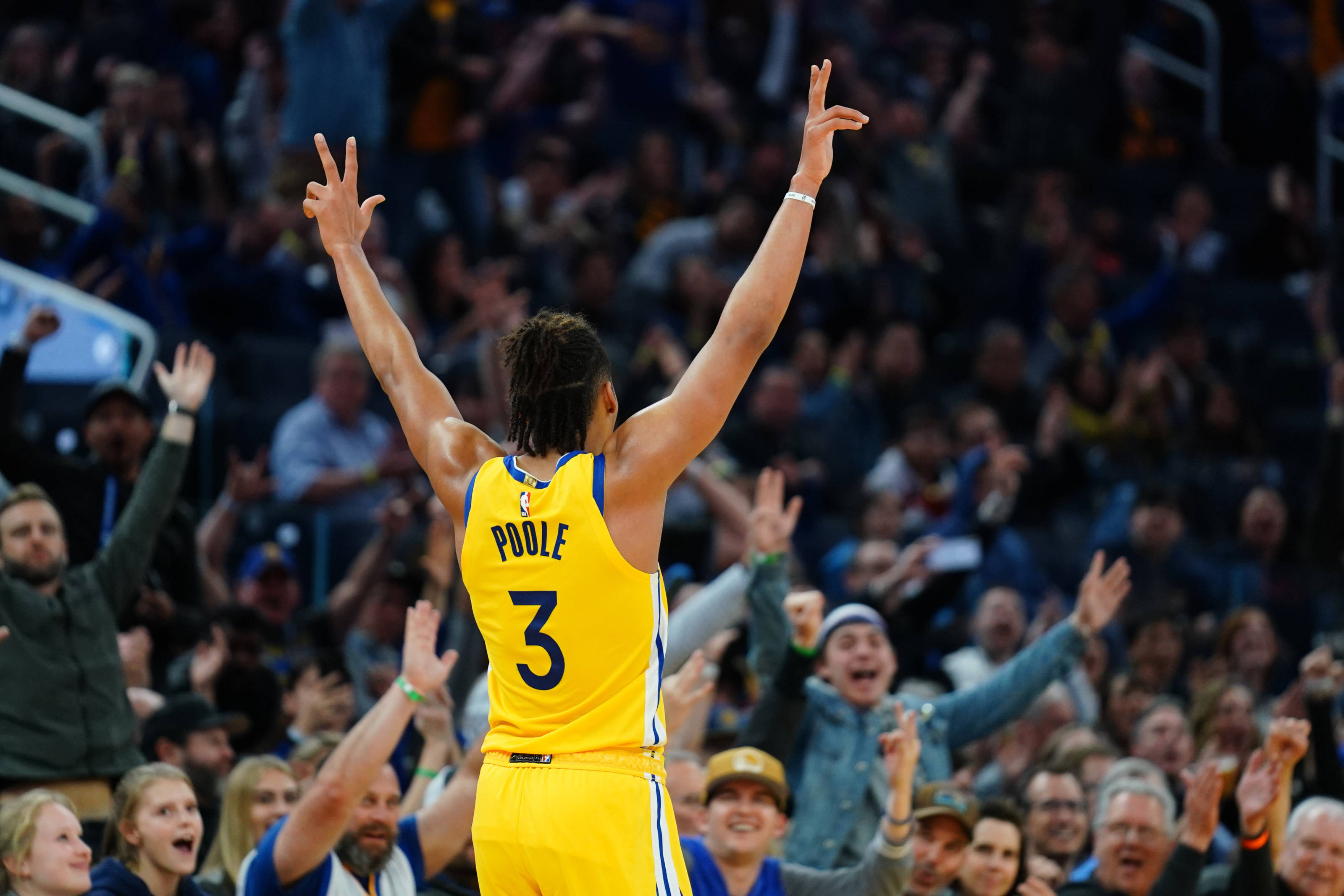 Jordan Poole 桌布 壁紙 — 一名身穿黃色球衣、背號3號的籃球運動員高舉雙臂慶祝勝利，身後興奮的人群為他歡呼。