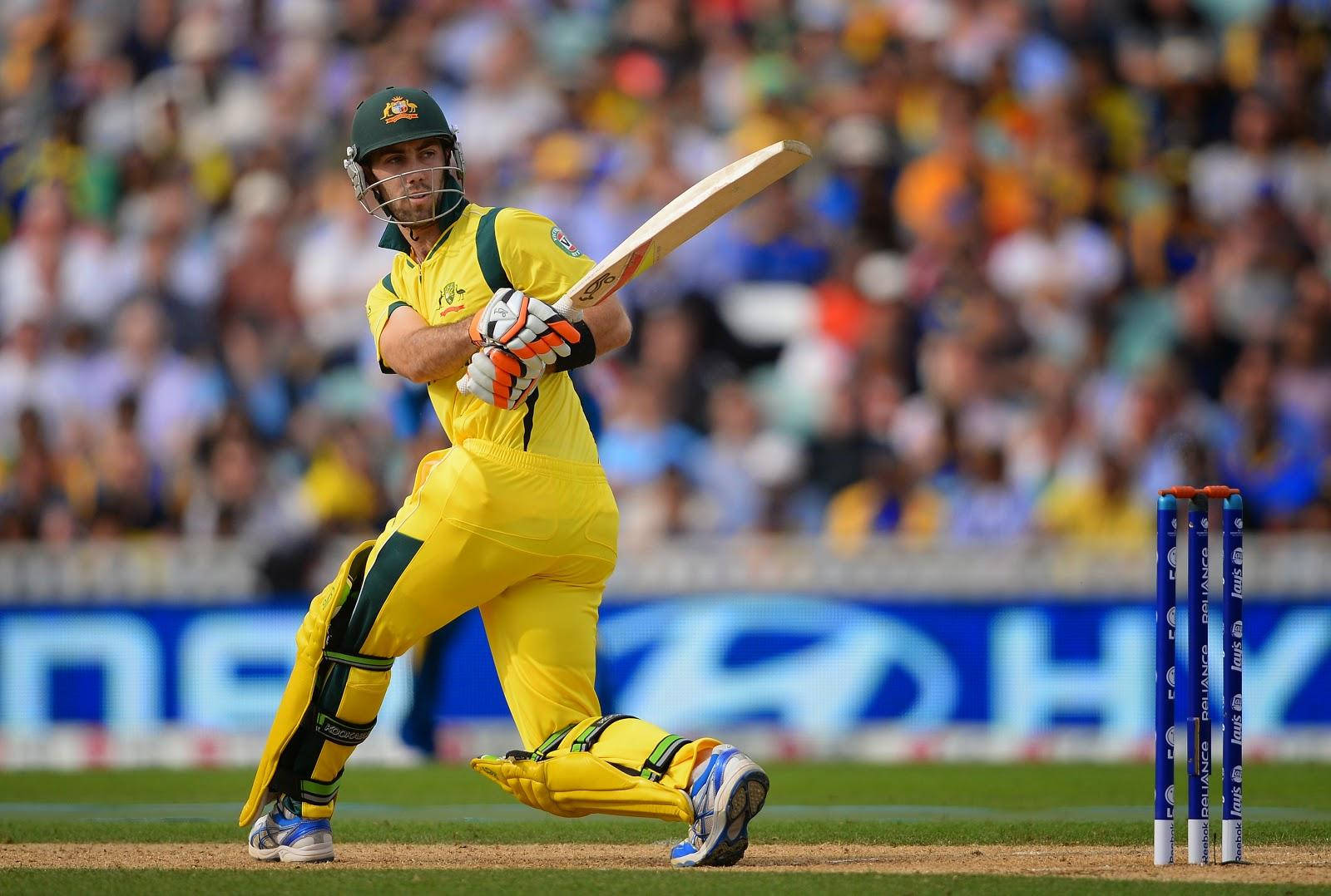australia cricket 桌布 壁紙 — 一名身穿黃色球衣的板球擊球手在日間比賽中強力揮動球棒，背景是模糊的人群。