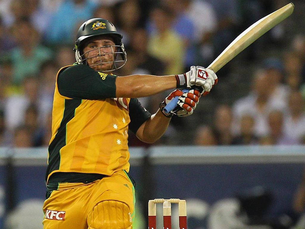 Aaron Finch 桌布 壁紙 — 一名身穿黃色球衣的澳洲板球運動員在球場燈光下的夜間比賽中強力揮棒。
