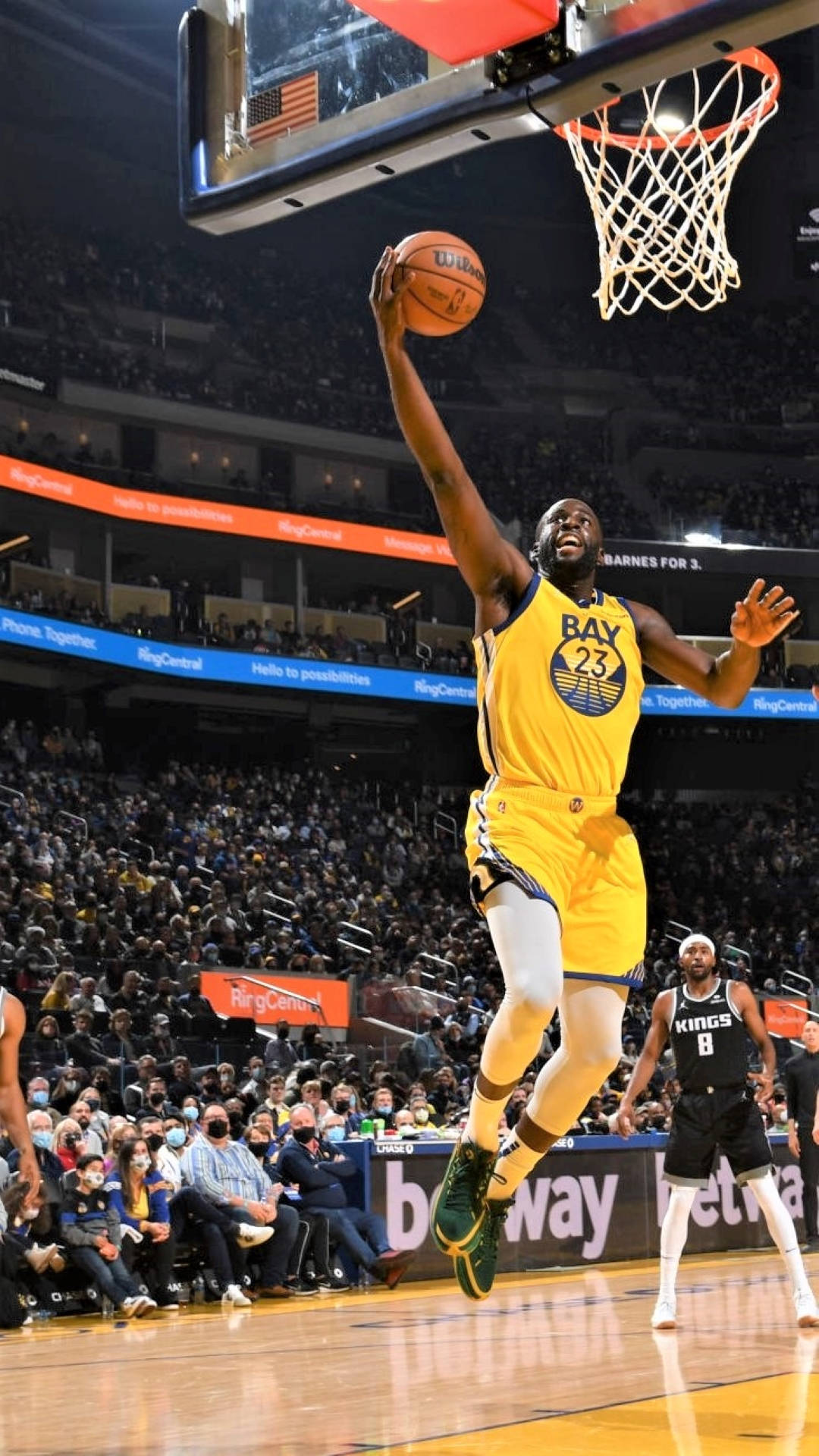 Draymond Green 桌布 壁紙 — 一名身穿黃色球衣的籃球運動員在擠滿觀眾的場館內，在明亮的場館燈光下灌籃。