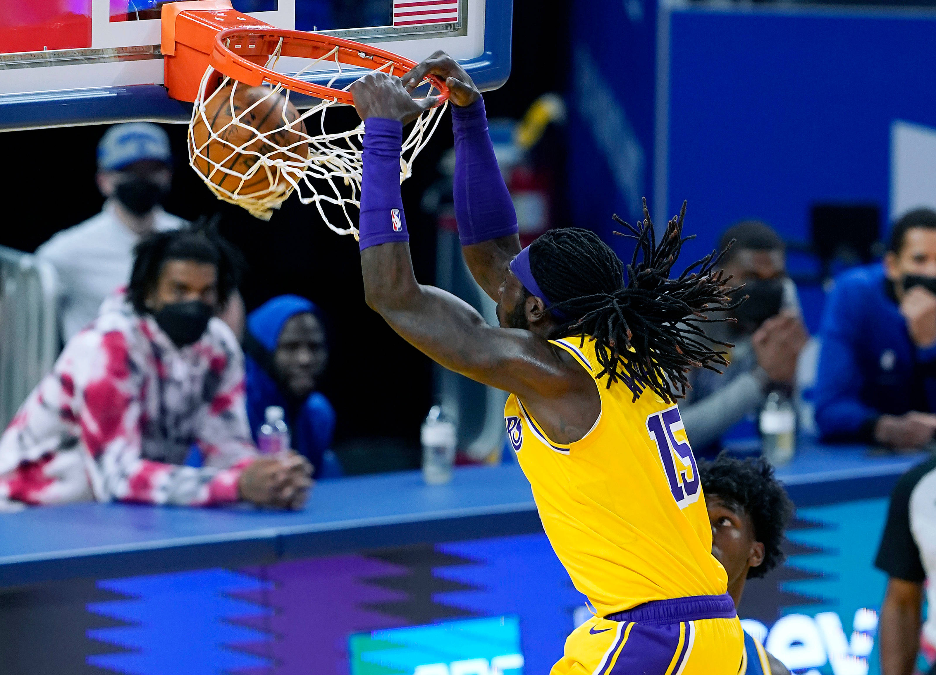 montrezl harrell 桌布 壁紙 — 一名身穿黃色球衣的籃球運動員用力灌籃，觀眾在場邊觀看。