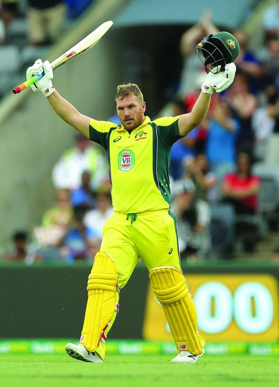 Aaron Finch 桌布 壁紙 — 一名身穿黃色裝備的澳洲板球運動員在綠色場地上高舉球棒和頭盔，勝利慶祝。