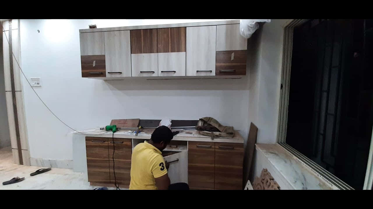 Man 桌布 壁紙 — 一名身穿黃色襯衫的男子在夜間空蕩蕩的房間裡，在明亮的人造光下安裝木製廚房櫥櫃。