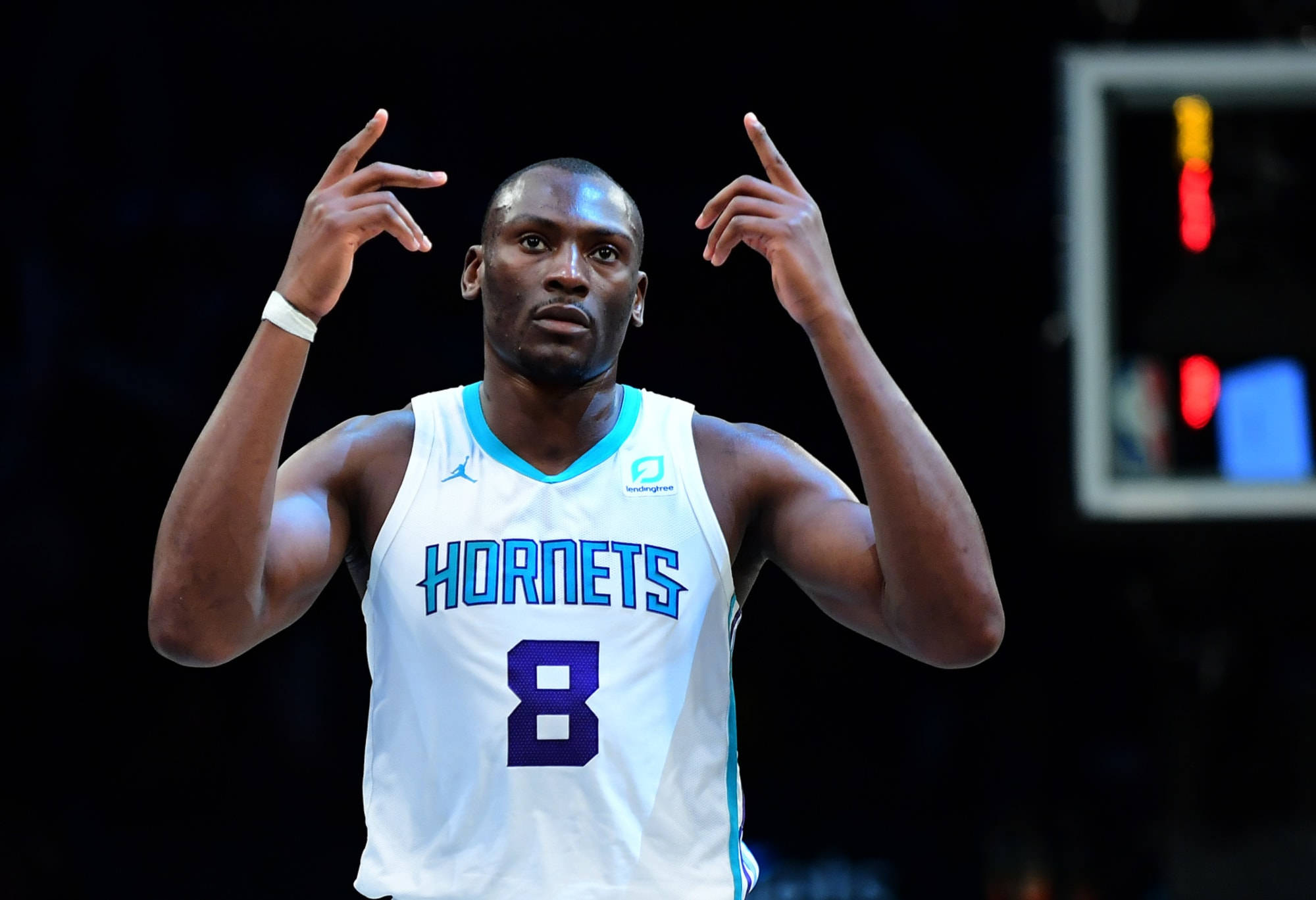 Hornets 桌布 壁紙 — 一名身穿黃蜂隊球衣的籃球運動員在明亮的場館燈光下，在比賽中激烈地做手勢。