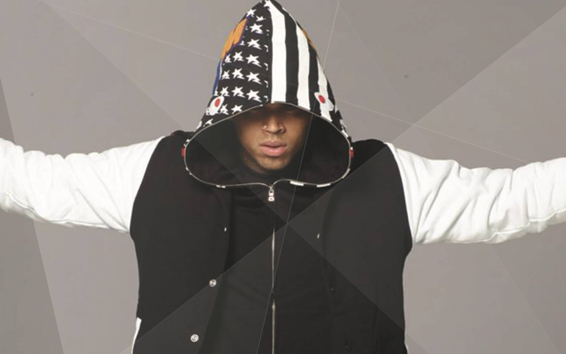 Chris Brown 桌布 壁紙 — 一名身穿黑白星星圖案連帽衫的男子，雙臂張開，背景為幾何灰色。