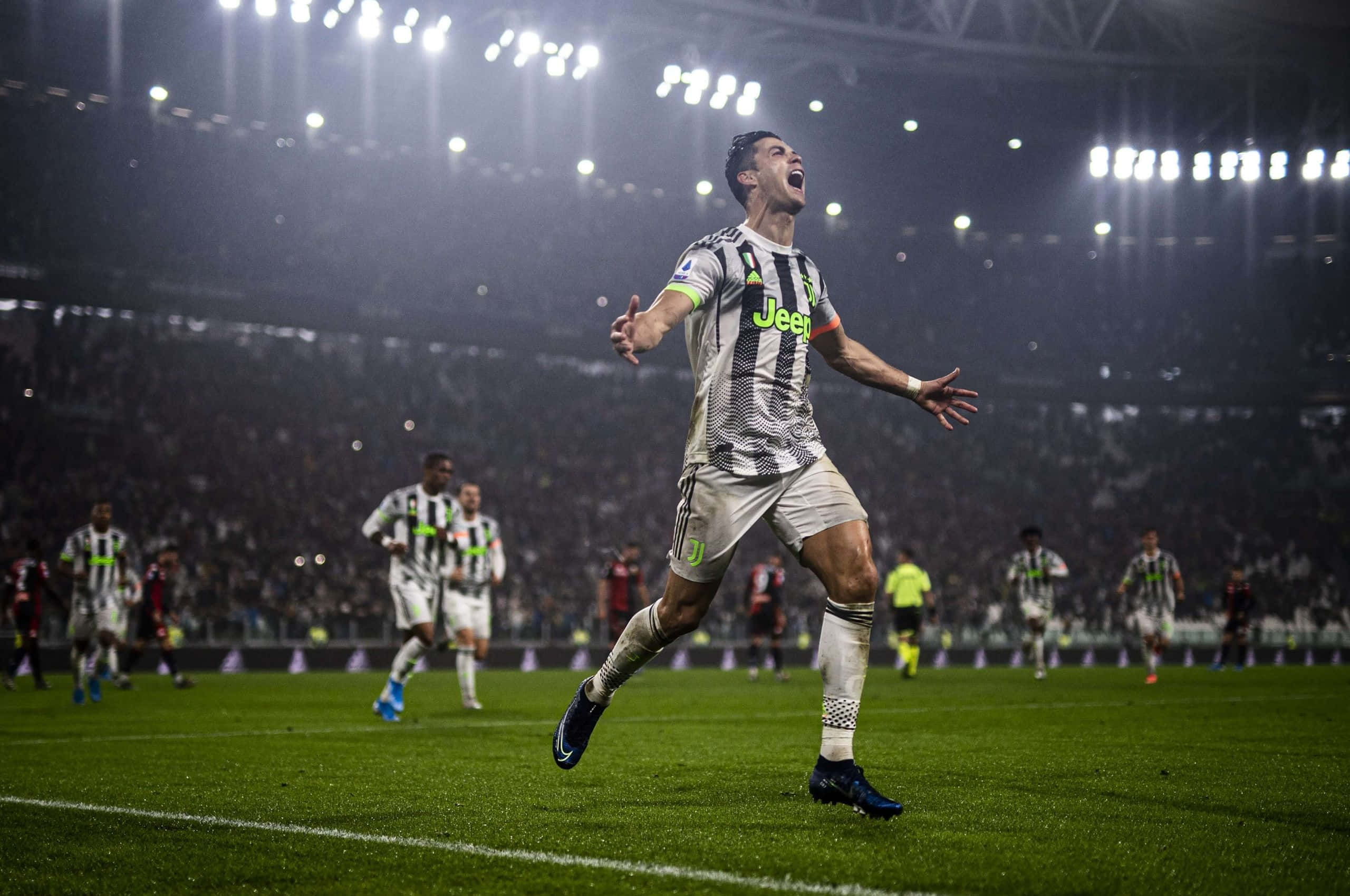 Ronaldo 桌布 壁紙 — 一名身穿黑白條紋球衣的足球員在夜間燈光明亮的球場上勝利慶祝。