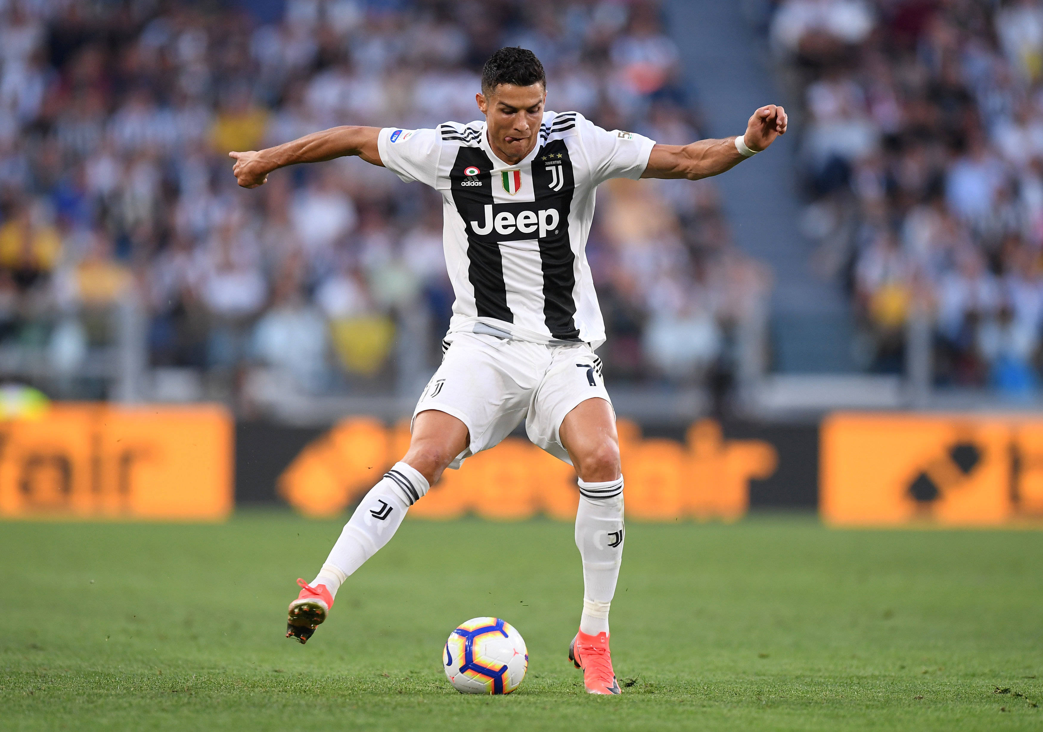 Ronaldo 桌布 壁紙 — 一名身穿黑白條紋球衣的足球員在綠色球場上踢一個色彩繽紛的球，背景有模糊的觀眾。