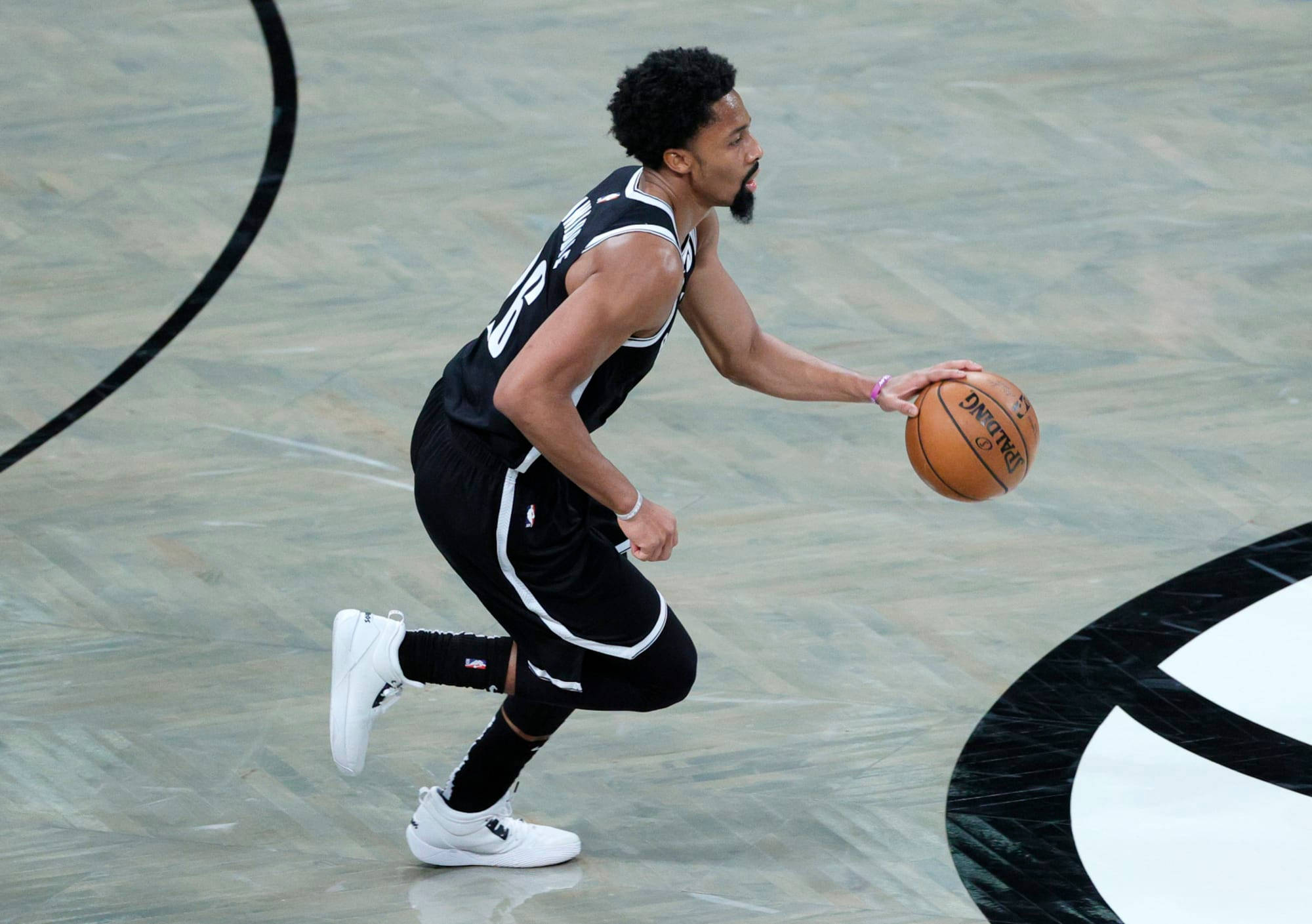 spencer dinwiddie 桌布 壁紙 — 一名身穿黑白球衣的籃球運動員在光滑的球場上運球，球場上有鮮明的球隊標誌。