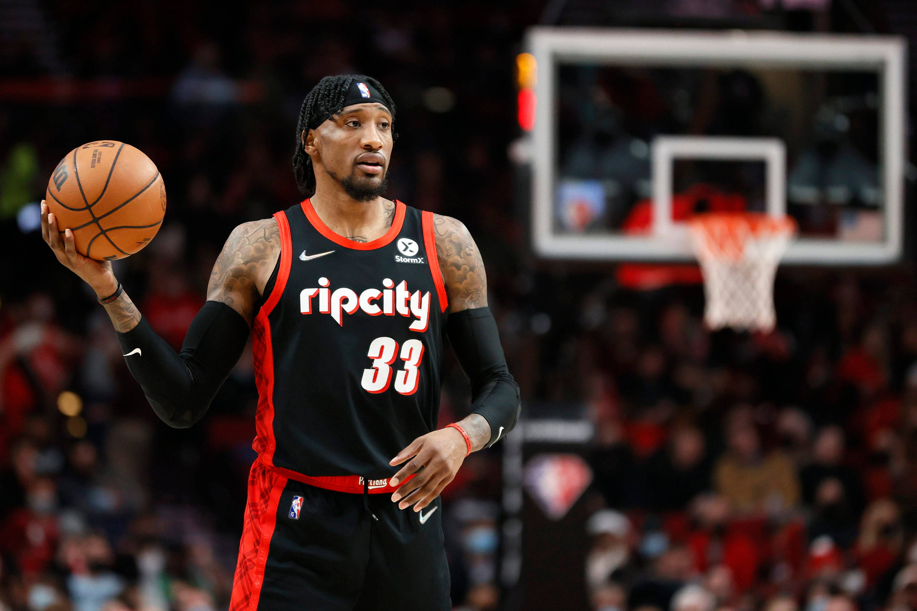 robert covington 桌布 壁紙 — 一名身穿黑紅色 'Rip City' 球衣的籃球運動員在球場燈光下比賽中持球，身後有模糊的人群和籃框。