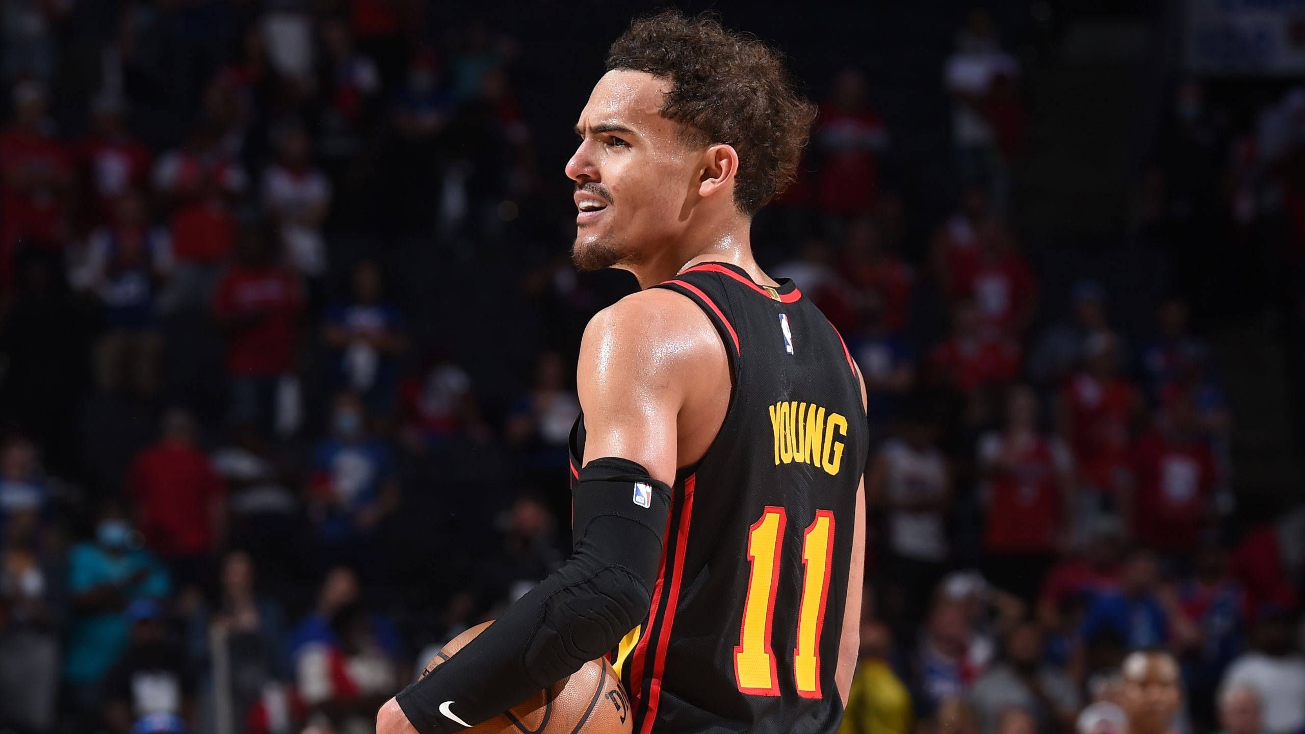 Hawks 桌布 壁紙 — 一名身穿黑紅色球衣、背號11的籃球運動員在明亮的場館燈光下運球比賽。