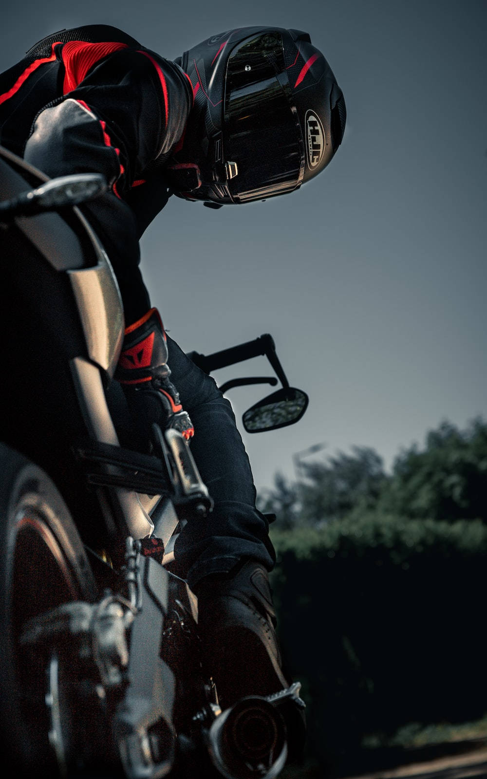 Bike Rider 桌布 壁紙 — 一名身穿黑紅色裝備的摩托車手，在昏暗的天空下，騎著流線型摩托車傾斜入彎。