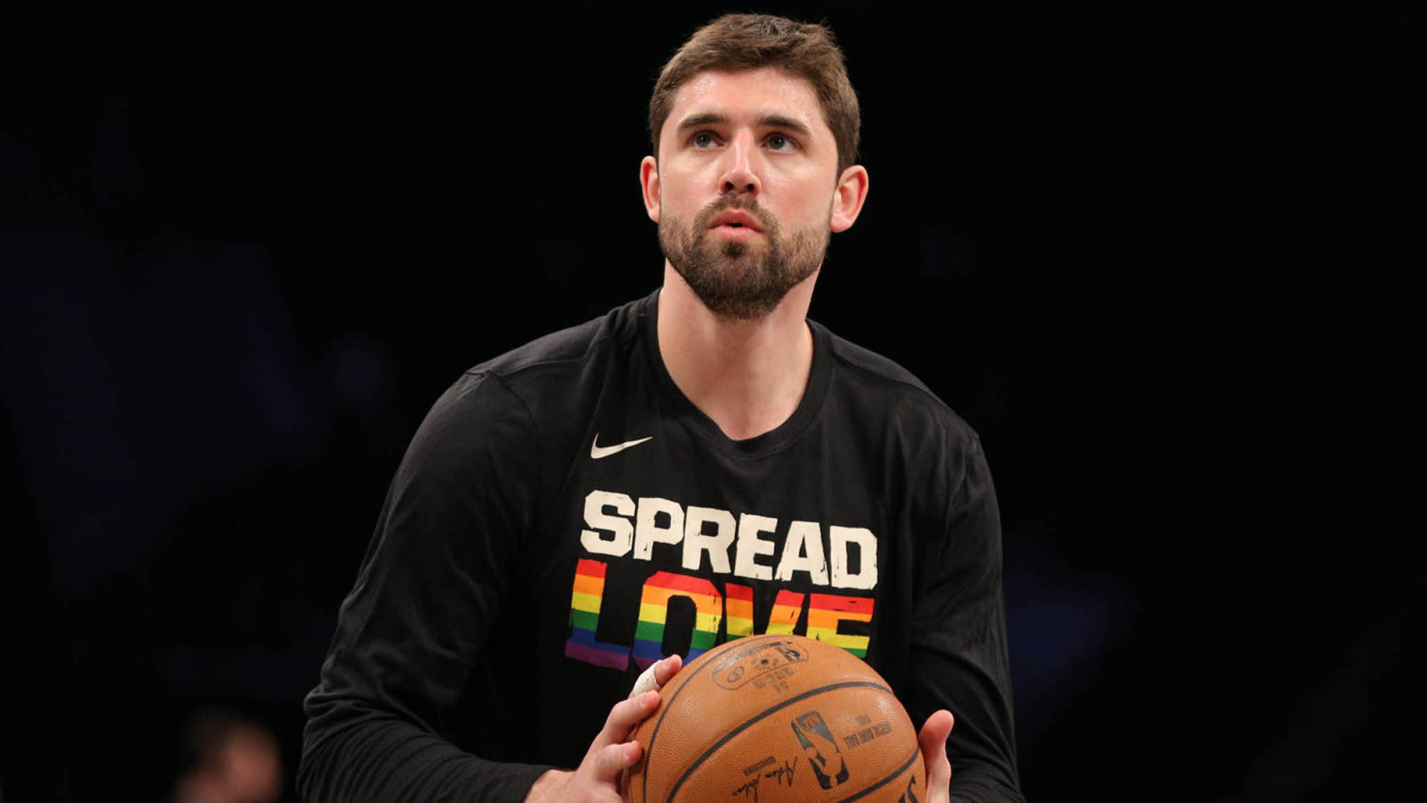 joe harris 桌布 壁紙 — 一名身穿黑色 'Spread Love' 彩虹T恤的籃球運動員在深色背景前手持籃球。