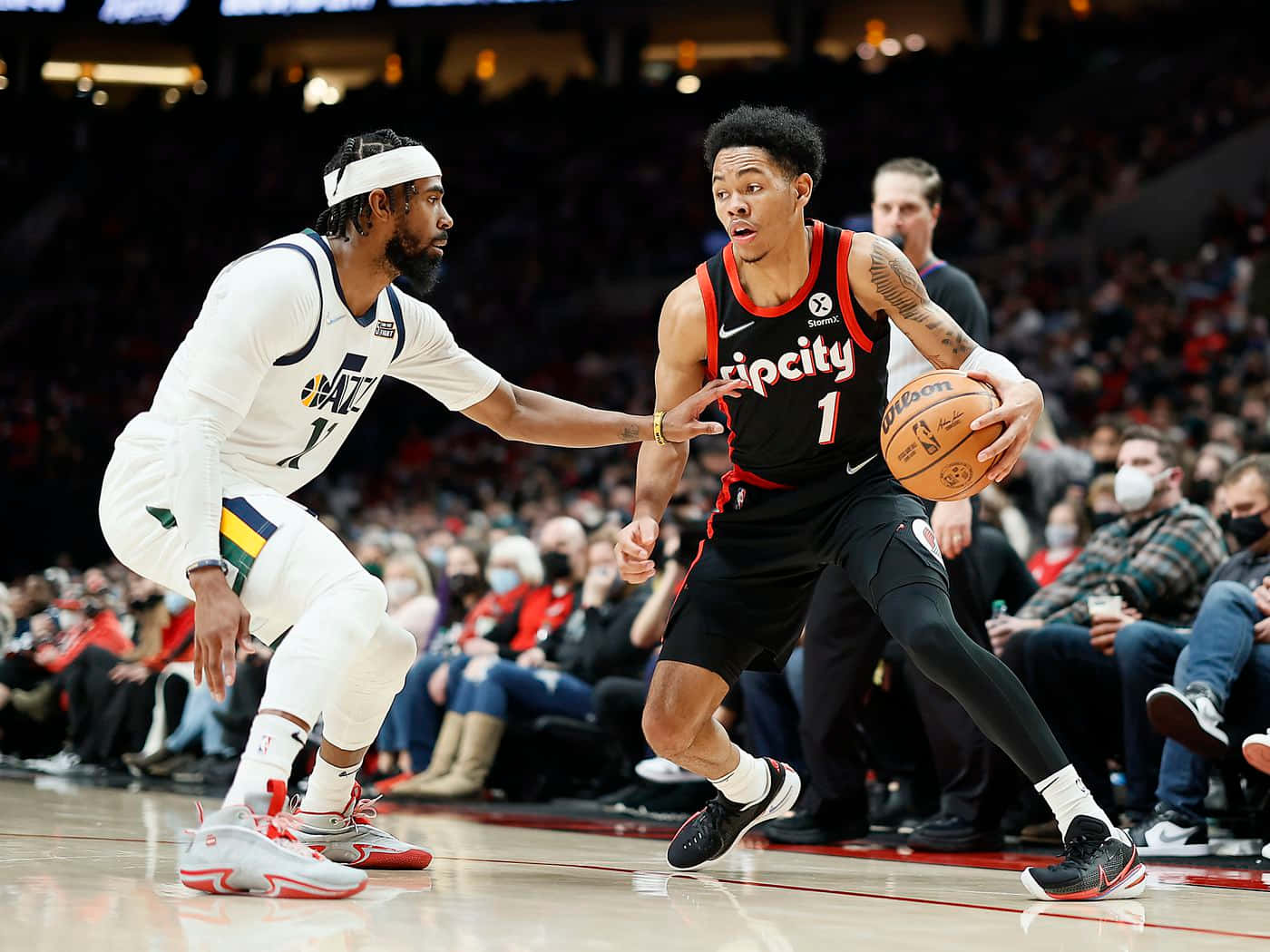 mike conley 桌布 壁紙 — 一名身穿黑色「Tip City」球衣的籃球運動員在現場比賽中運球，同時被一名身穿白色爵士隊球衣的對手緊密防守。