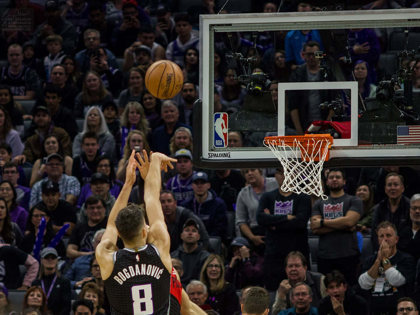 NBA 桌布 壁紙 — 一名身穿黑色8號球衣的籃球運動員跳起投籃，球劃出一道弧線飛向籃框，觀眾專注地觀看。