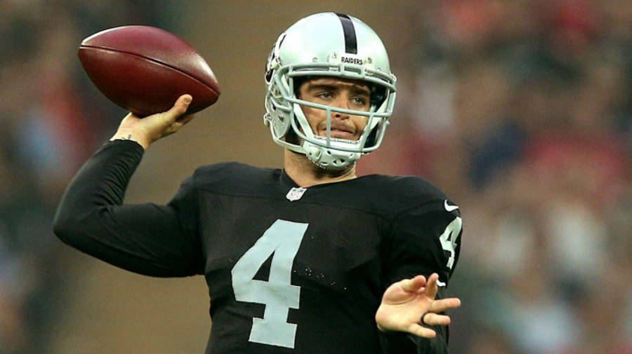 NFL 桌布 壁紙 — 一名身穿黑色Raiders球衣（4號）的美式足球四分衛正在球場燈光下準備傳球。