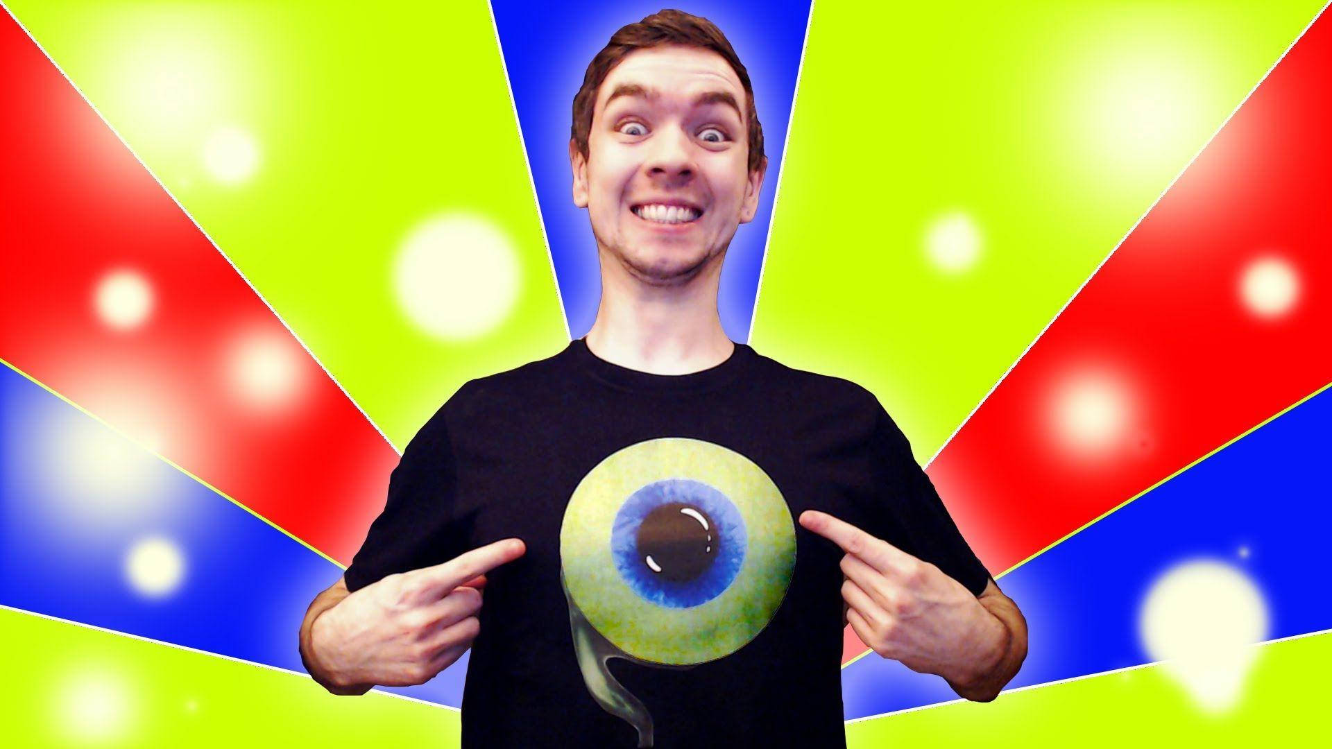 Jacksepticeye 桌布 壁紙 — 一名身穿黑色T恤、上面有巨大眼睛圖案的男人，在充滿活力的紅、藍、綠放射狀背景和發光球體前指著它。