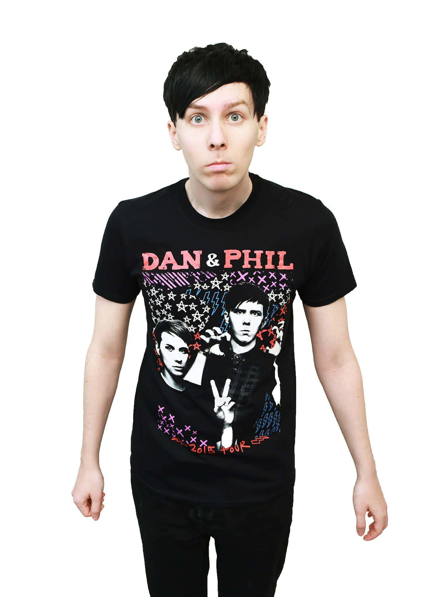 dan and phil 桌布 壁紙 — 一名身穿黑色T恤、印有彩色Dan & Phil巡迴圖案的男人，在白色背景前露出驚訝表情。