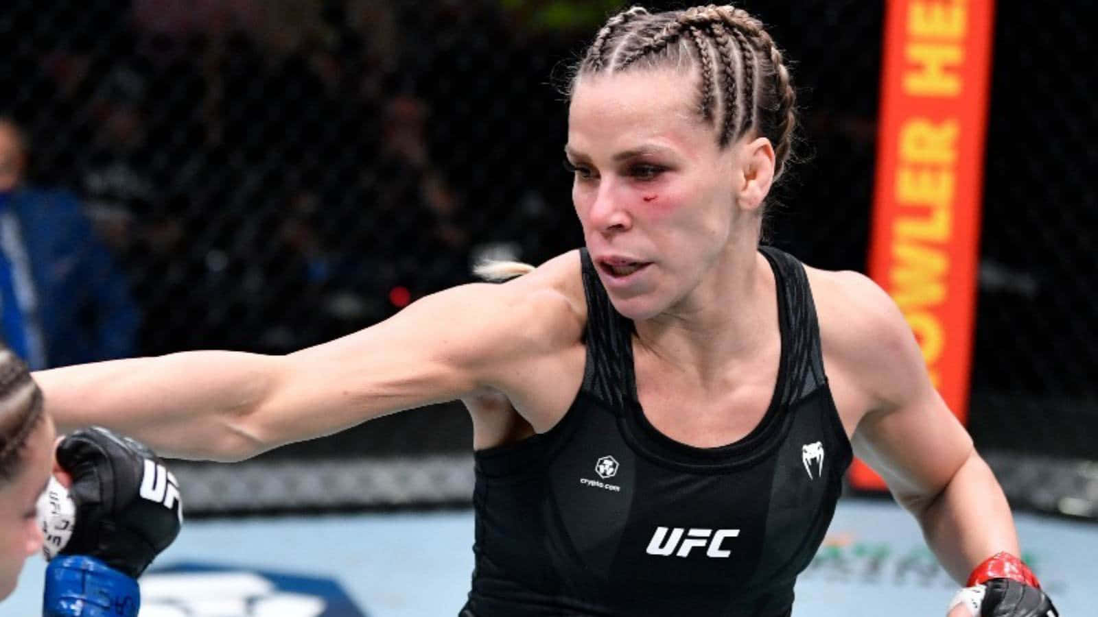 桌布 壁紙 — 一名身穿黑色UFC背心的女性MMA拳手在八角籠內進行激烈比賽時打出強力一拳。