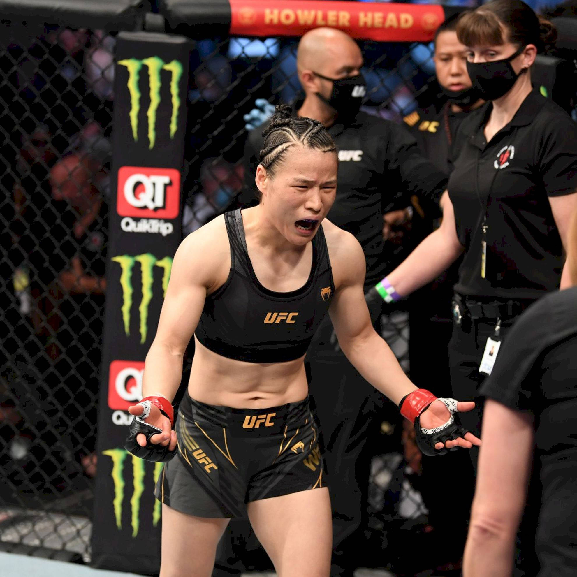 Champion 桌布 壁紙 — 一名身穿黑色UFC裝備的女MMA拳手在八角籠內咆哮勝利，附近有品牌標誌和戴面具的官員。