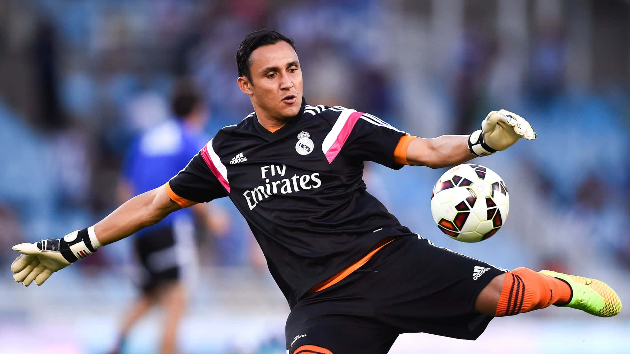 Keylor Navas 桌布 壁紙 — 一名身穿黑色和橙色球衣的足球守門員動態地飛身撲接一個黑白圖案的球。