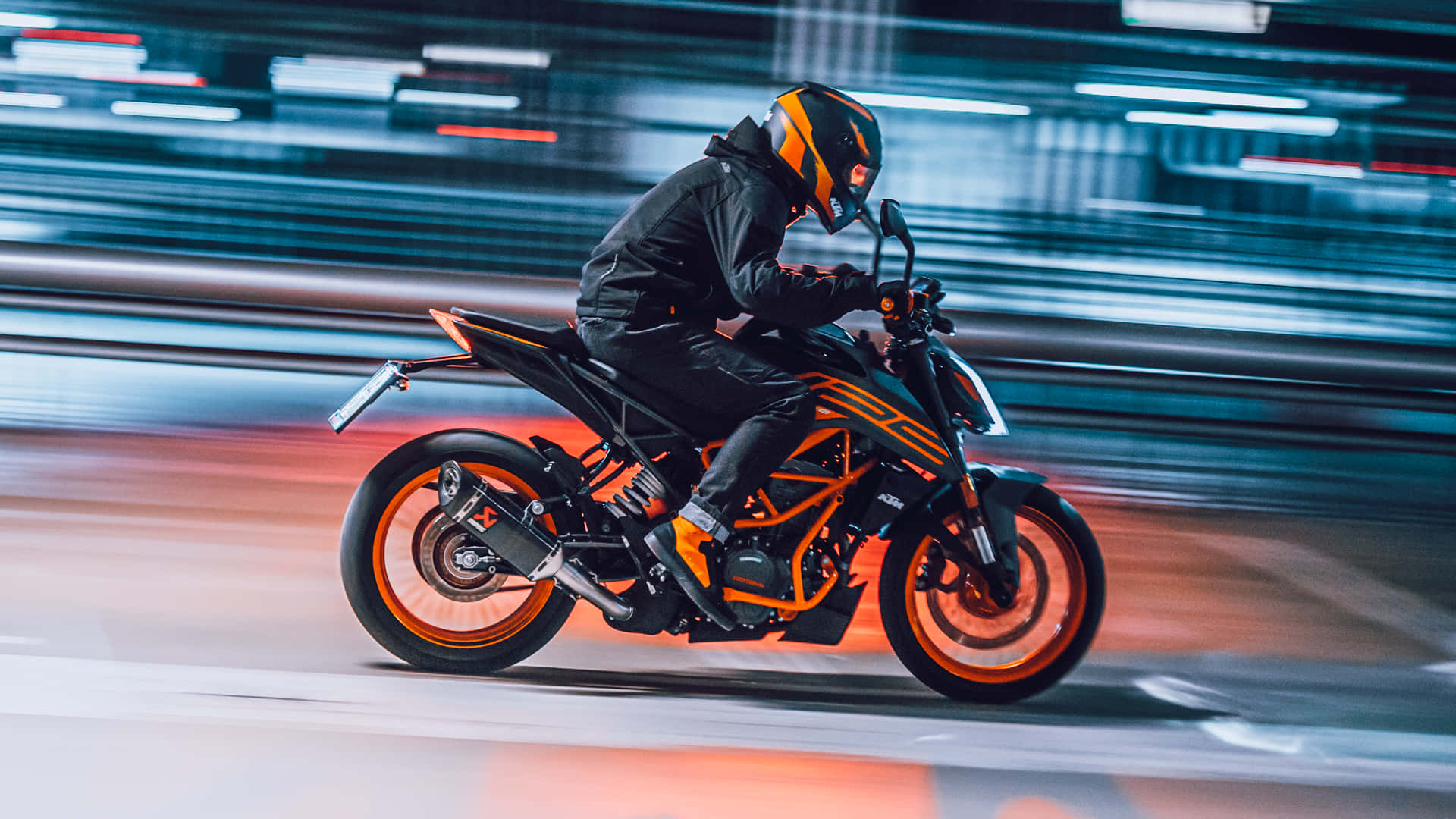 KTM 摩托車 桌布 壁紙 — 一名身穿黑色和橙色裝備的摩托車騎士，在霓虹燈閃爍的都市夜晚高速奔馳，身後留下光跡。