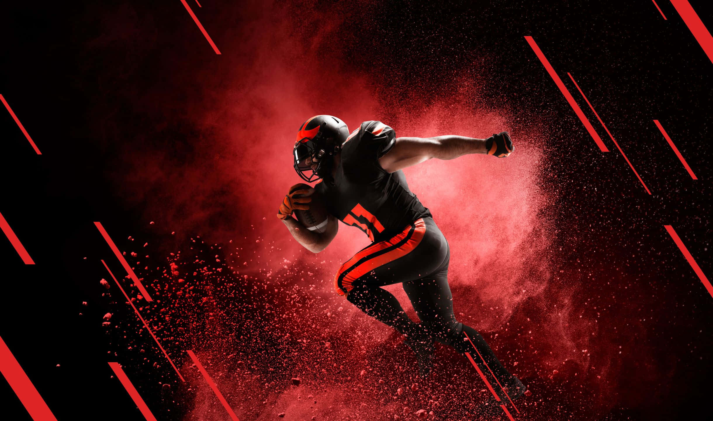 2440x1440 Football 桌布 壁紙 — 一名身穿黑色和橙色裝備的美式足球員在帶有紅色條紋的深色背景下，衝過一陣紅色粉末爆發。