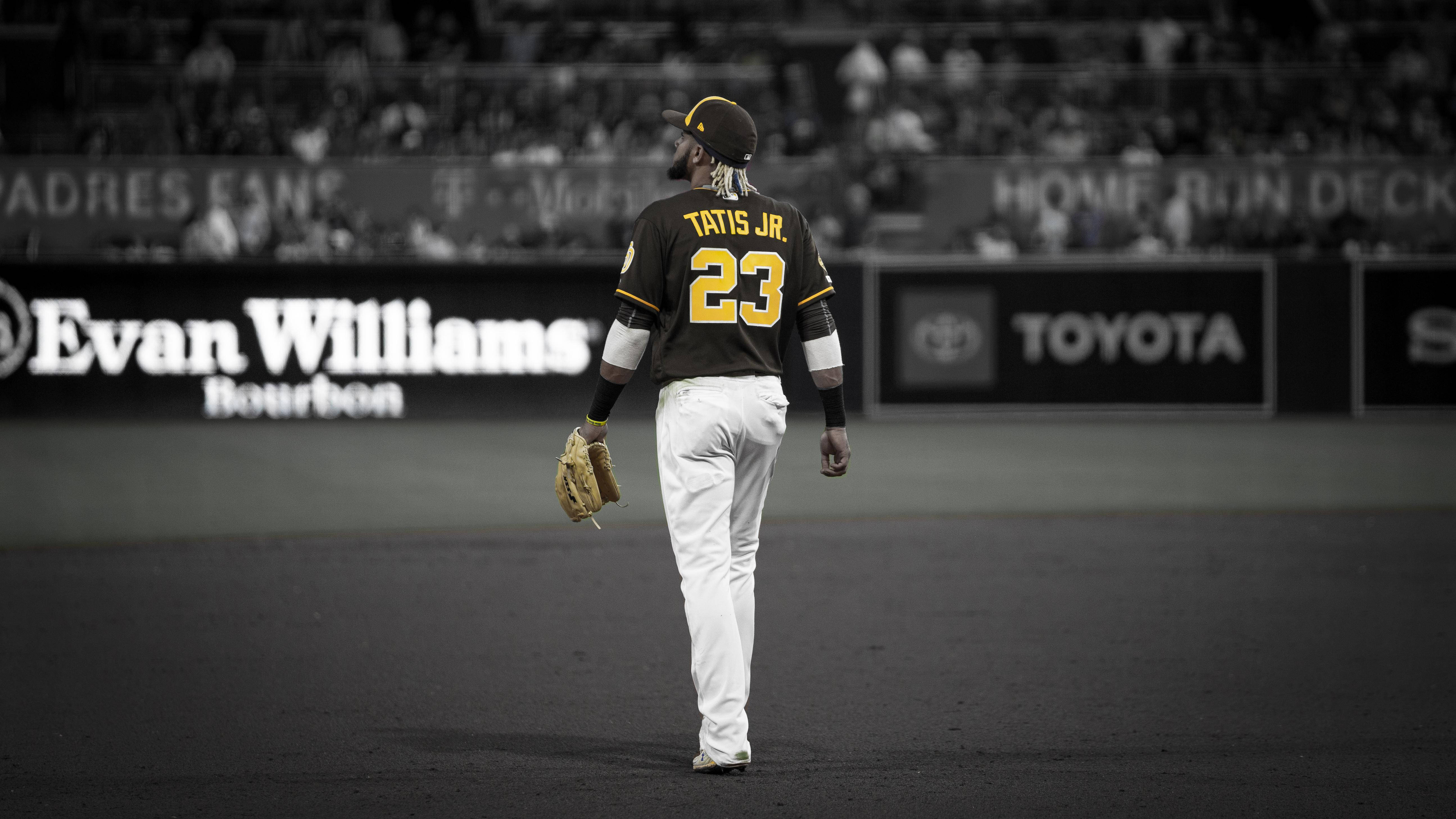 Tatis 桌布 壁紙 — 一名身穿黑色和金色球衣、背號23的棒球運動員在昏暗的球場上背對鏡頭走開，背景是模糊的體育場燈光和廣告。