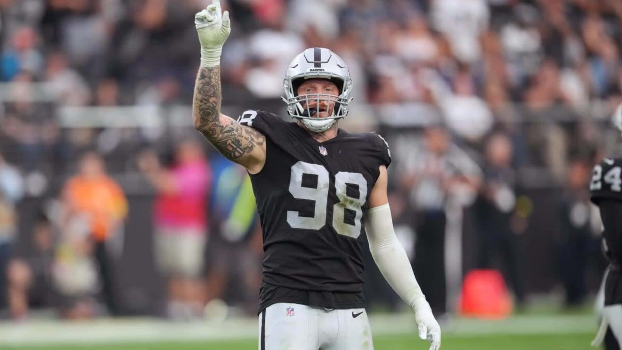 Las Vegas Raiders 桌布 壁紙 — 一名身穿黑色和銀色球衣的足球員在綠色球場上舉起戴手套的手慶祝，背景是模糊的人群。